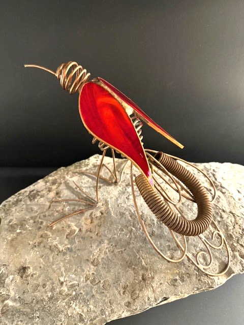 #A113 - Red Iridized Bird - A bold sculptural flourish, this unique standing sculpture features a metal and glass bird that reads like modern garden art - perfect as a decorative gift or sympathy accent. Perfect for a mantle, bedside table, or memorial display, the sculpture sets a contemplative, thoughtful tone that will make the person you're thinking of feel seen and remembered. The piece pairs a copper wire structure and arusty antique spring, with elongated iridized wing panels in red iridescent glass. This artful piece balances warm metallic sheen, translucent color, and artful design for visual impact without overwhelming a small space.   Ideal for someone who loves nature-inspired décor, contemporary keepsakes, or a meaningful sympathy gift, this sculpture arrives ready to display on a desk, shelf, or mantel. Its durable metal and glass components are designed for long-lasting presence; choose this when you want a lasting, artful reminder of care.  Shipping available - select Delivery, then message us to ship.