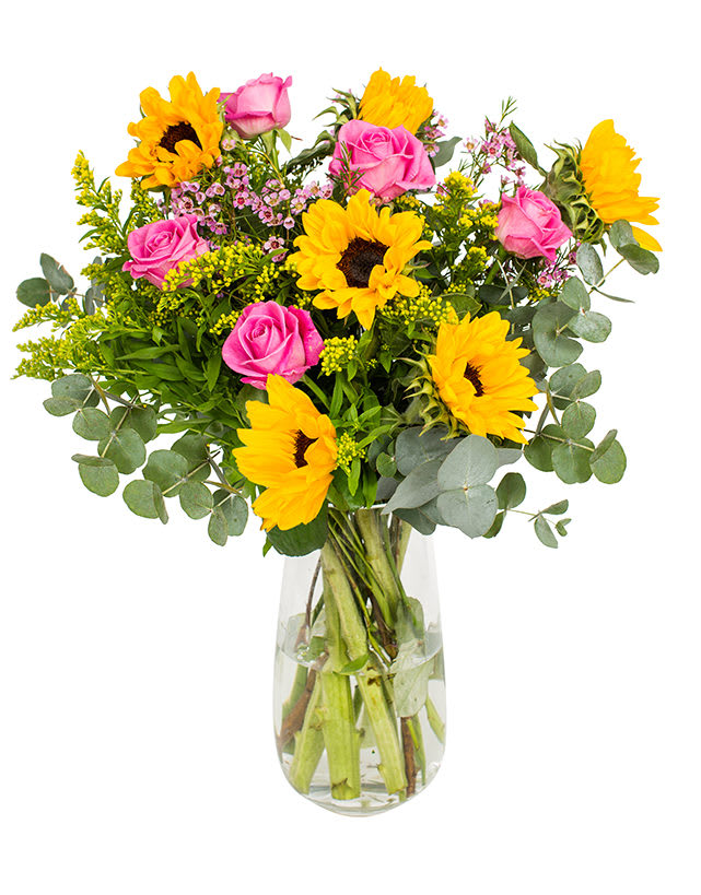 Bouquet of yellow sunflowers and pink roses in a clear glass vase