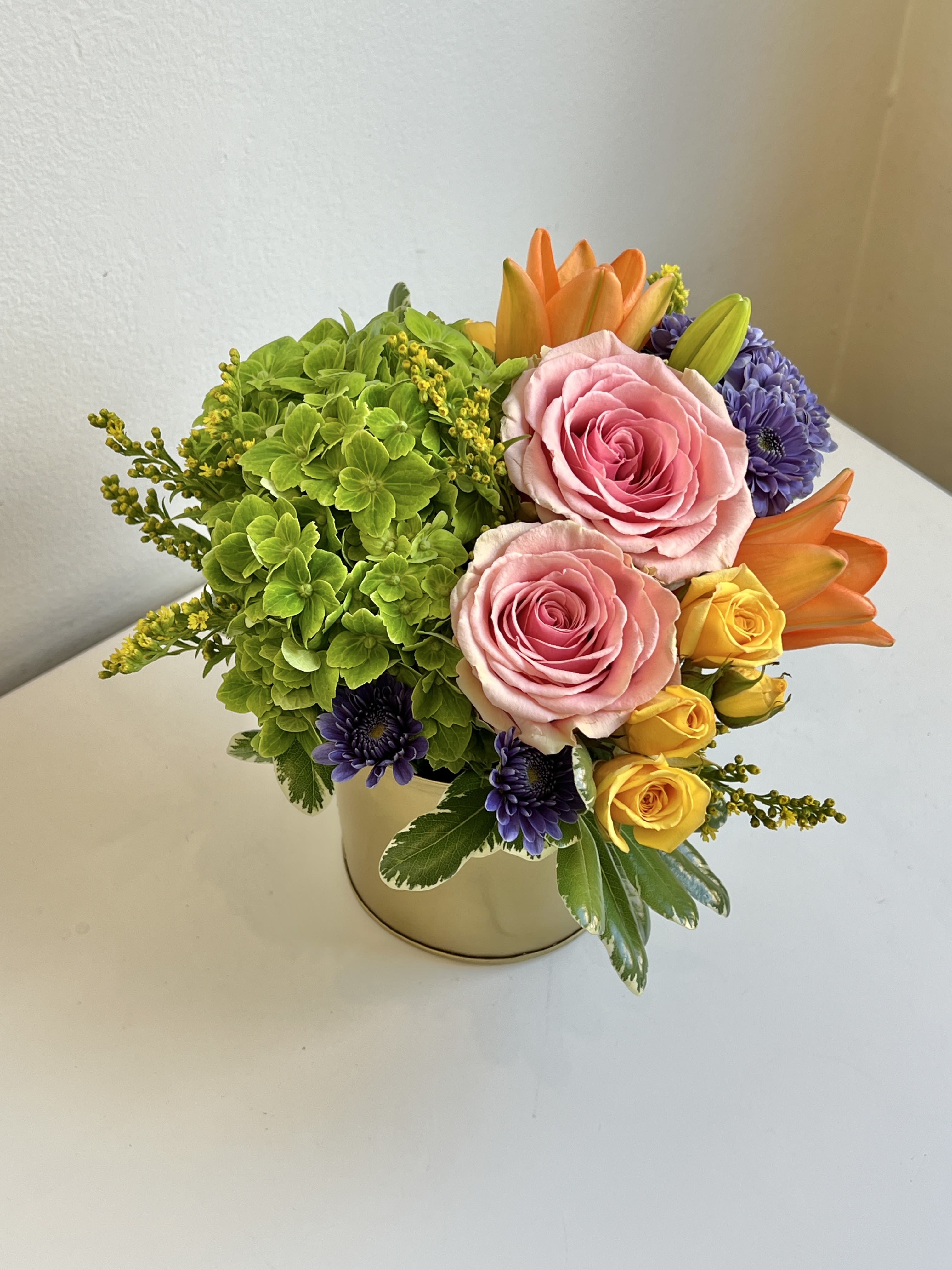 ADP-5 - Green Hydrangea, Spring Colored Roses, Lilies, Spray Roses and Mums With Assorted Foliage and Fillers in Gold Container.