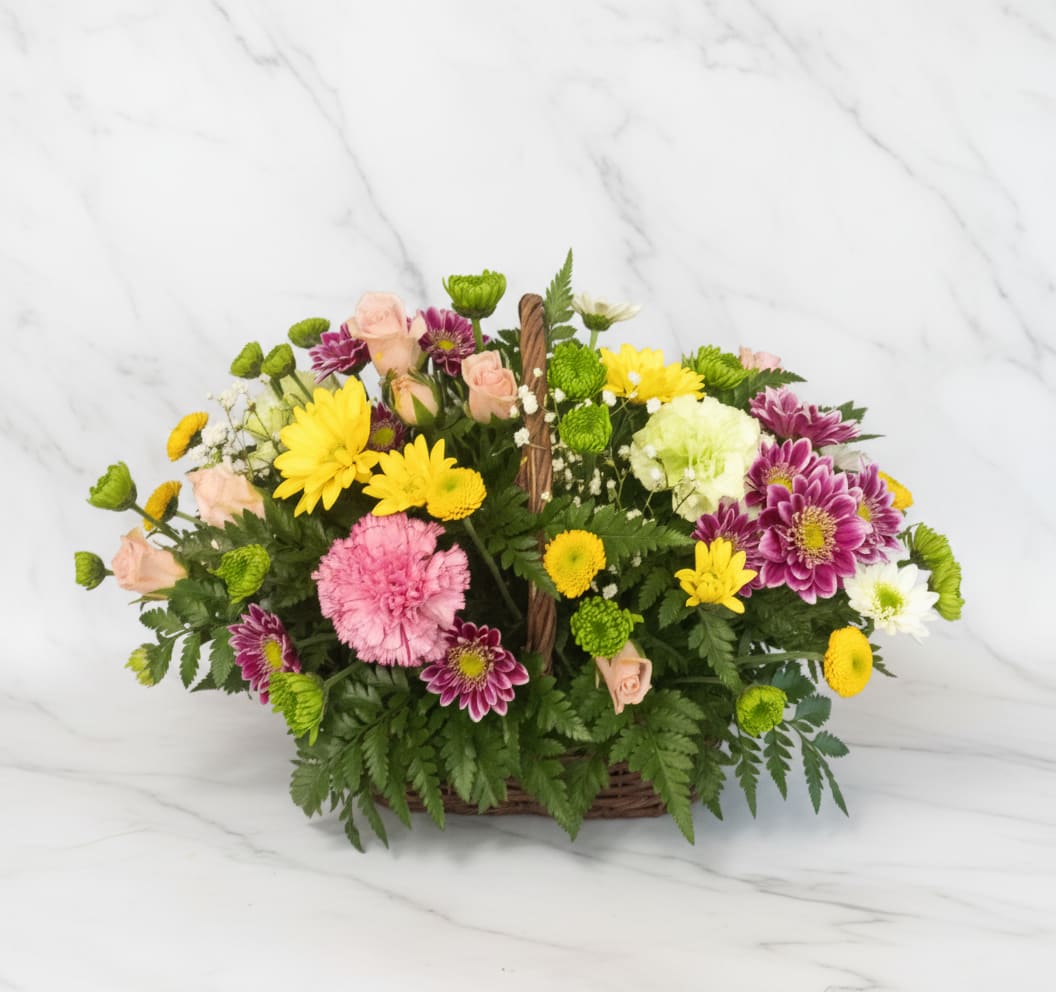 Mixed bouquet in a wicker basket with pink, yellow, white, and purple flowers