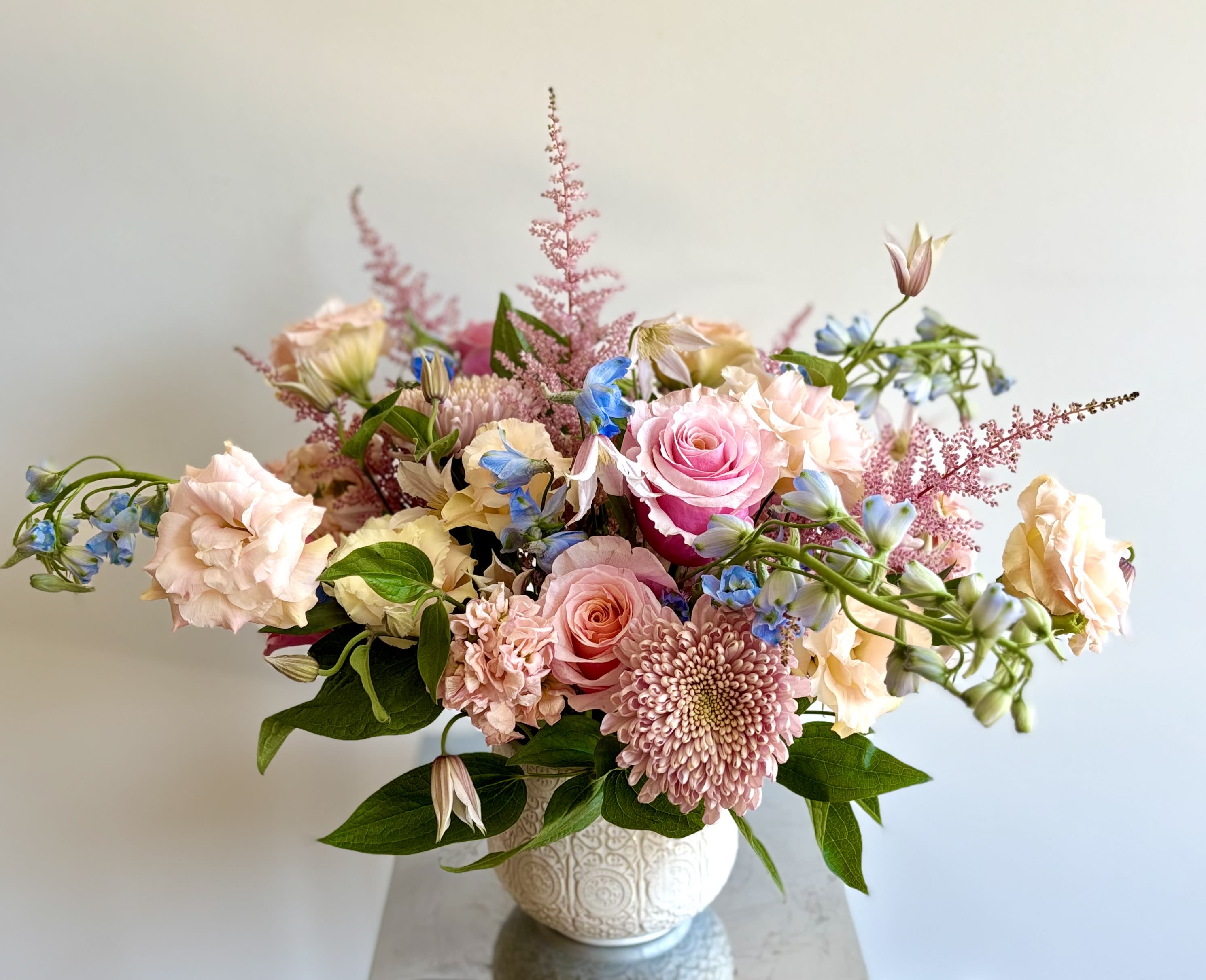 Pink and peach floral arrangement in a white vase