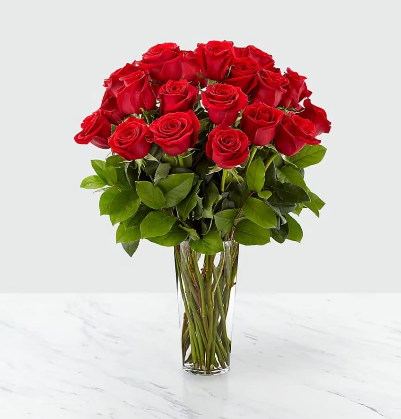 Tall clear glass vase filled with a large bouquet of long-stemmed red roses.