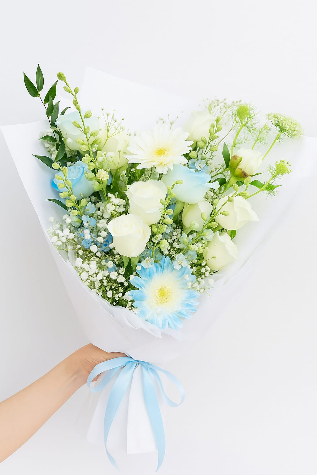 Bouquet of white and blue flowers wrapped in white paper with a blue ribbon