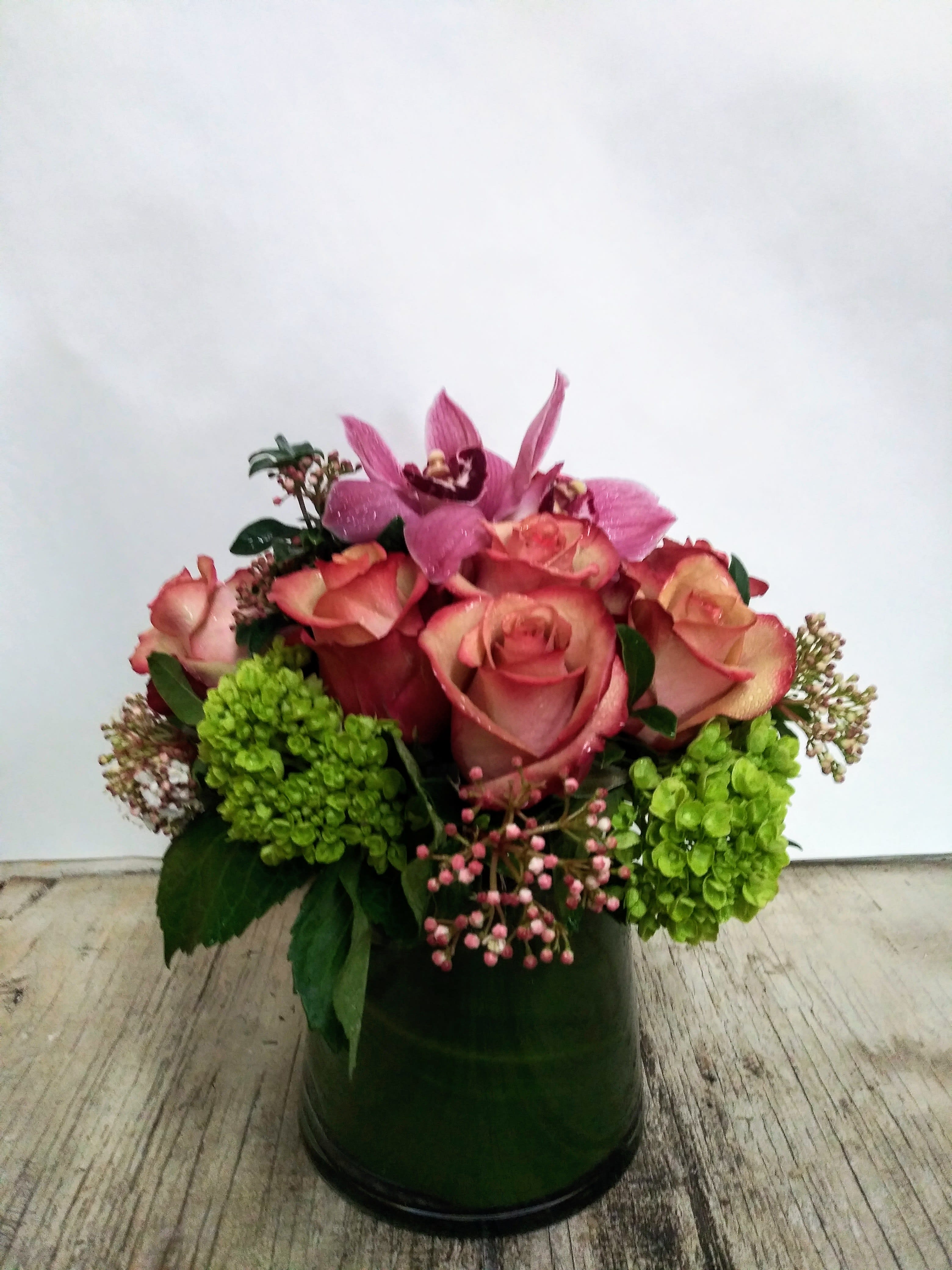 Pink roses and orchids arranged in a green vase
