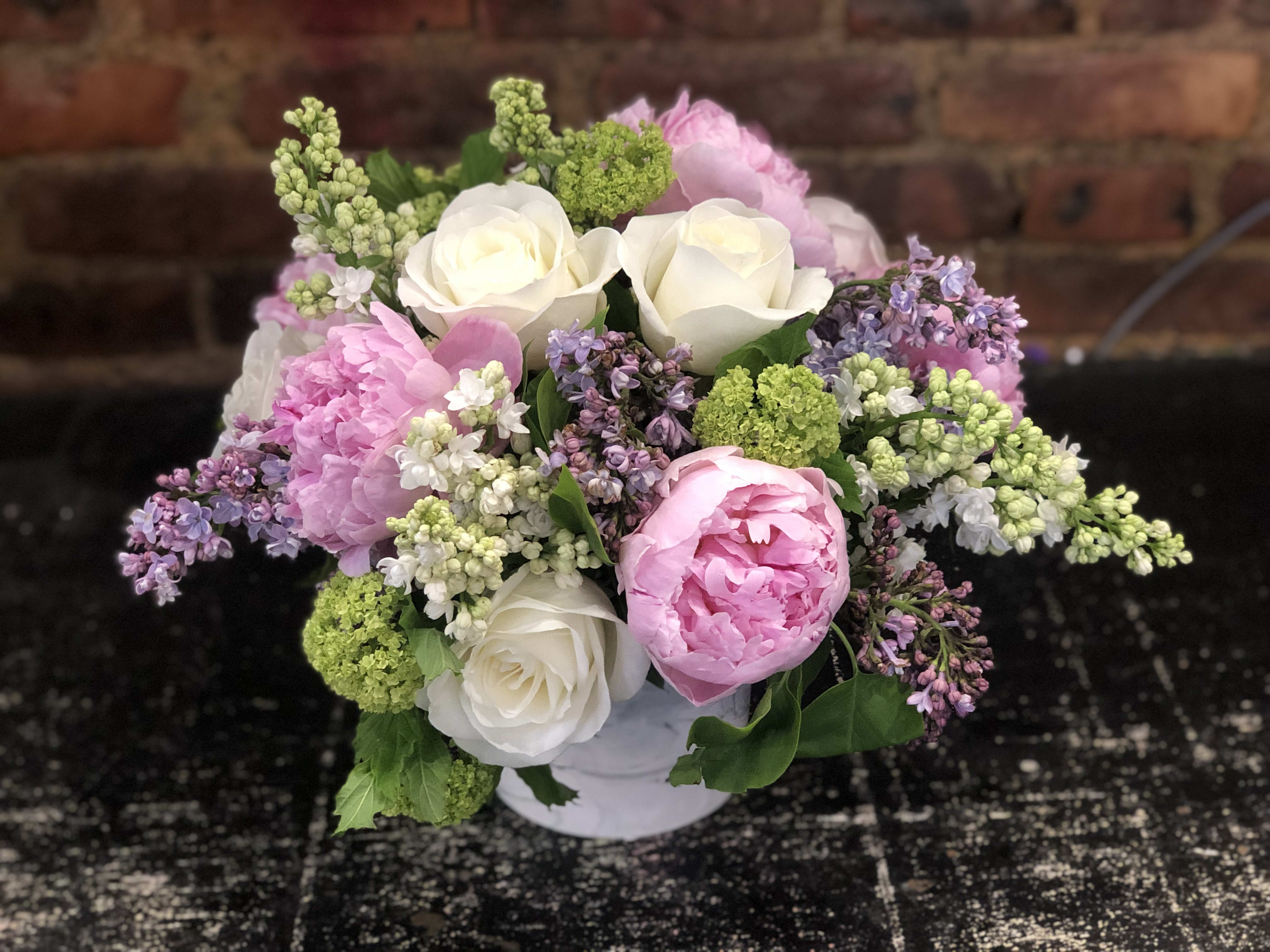Pink and white flower bouquet in a white container