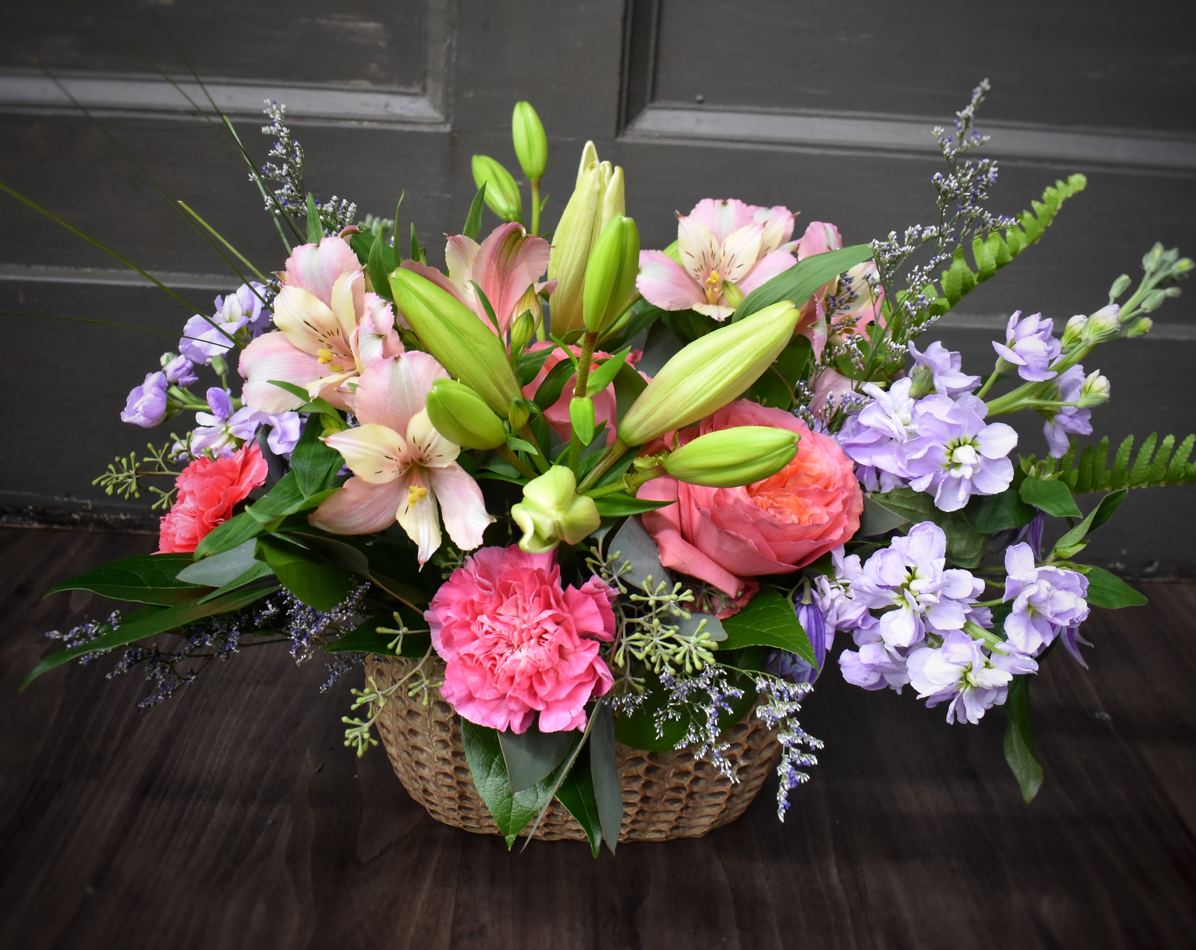 Basket arrangement of pink lilies, roses, and purple flowers