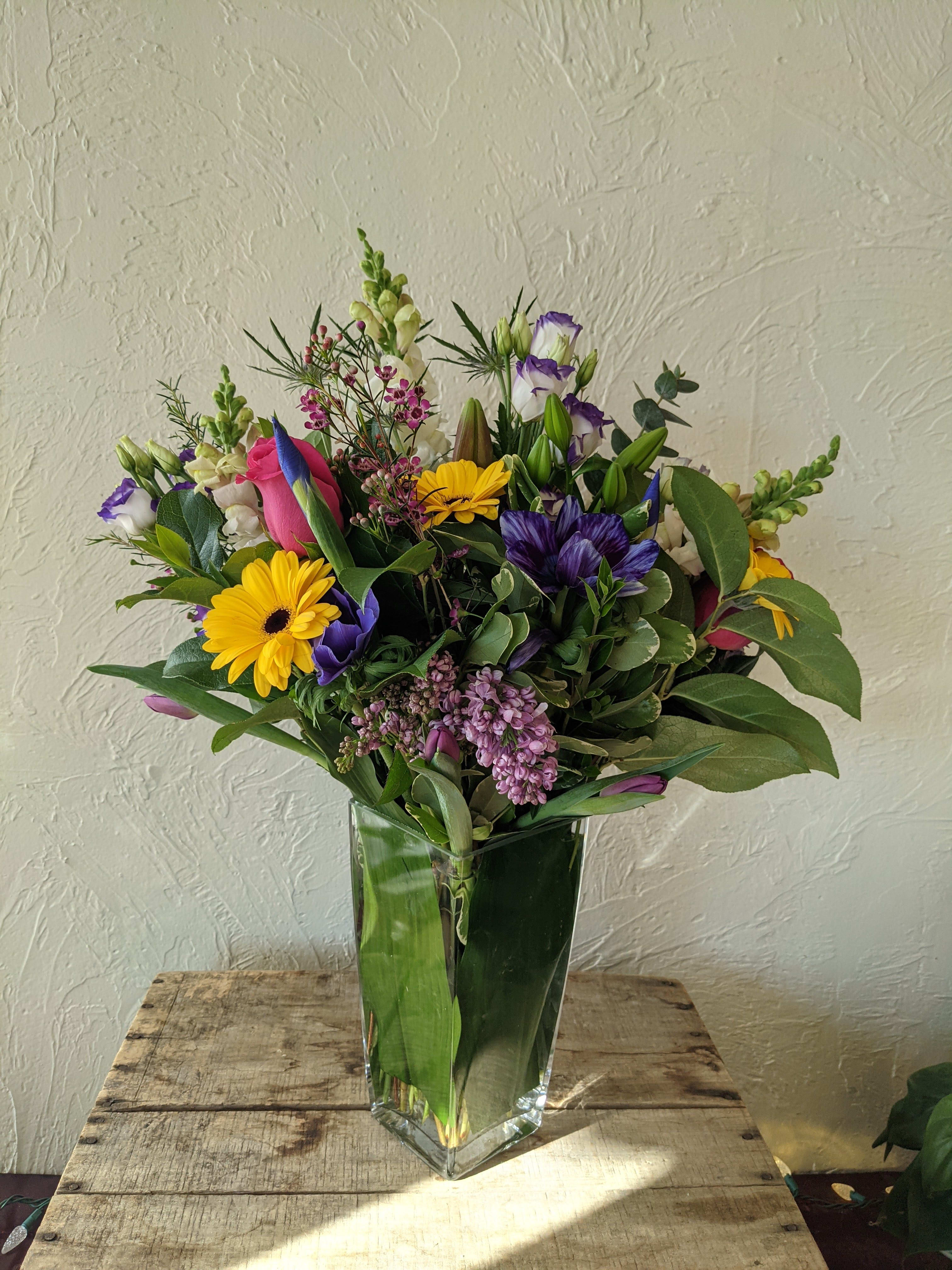 Designer's Choice - Tall (Mixed Colors) - Add a little height to your arrangement with our tall take on our signature Designer's Choice arrangement. As with the smaller version, these arrangements are bright, colorful and often feature seasonal flowers. The additional height allows us to use a wider selection of flowers and allows for a more voluminous arrangement. These pieces are for those who want a little more *umph* in their arrangement.  Please note: all pictures are examples of designer's choice arrangements and can not be requested specifically with this ordering option. If you are looking to order a custom arrangement please call our store directly.  Not available for Mother's Day