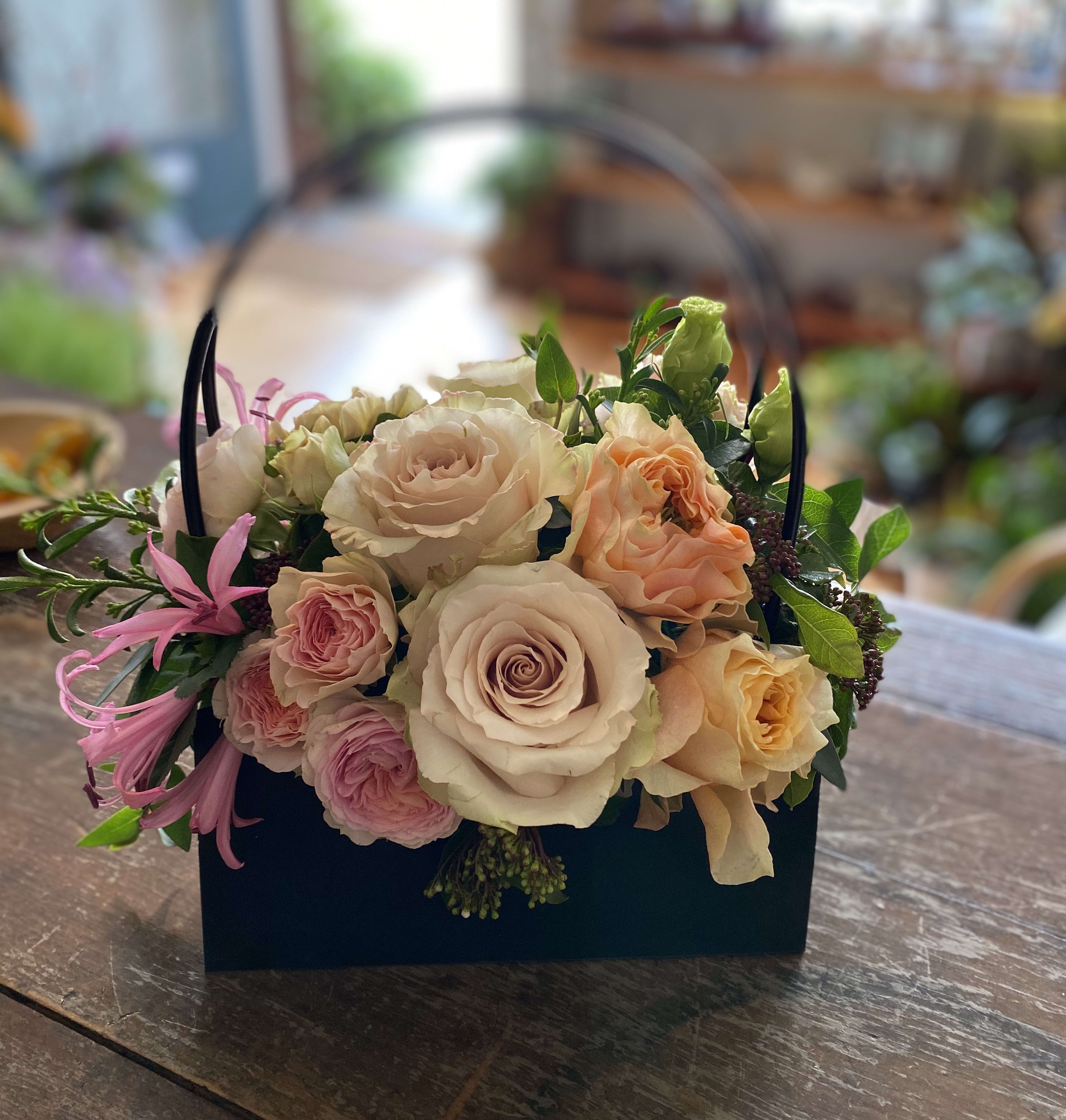 Basket of pastel roses with pink accent flowers