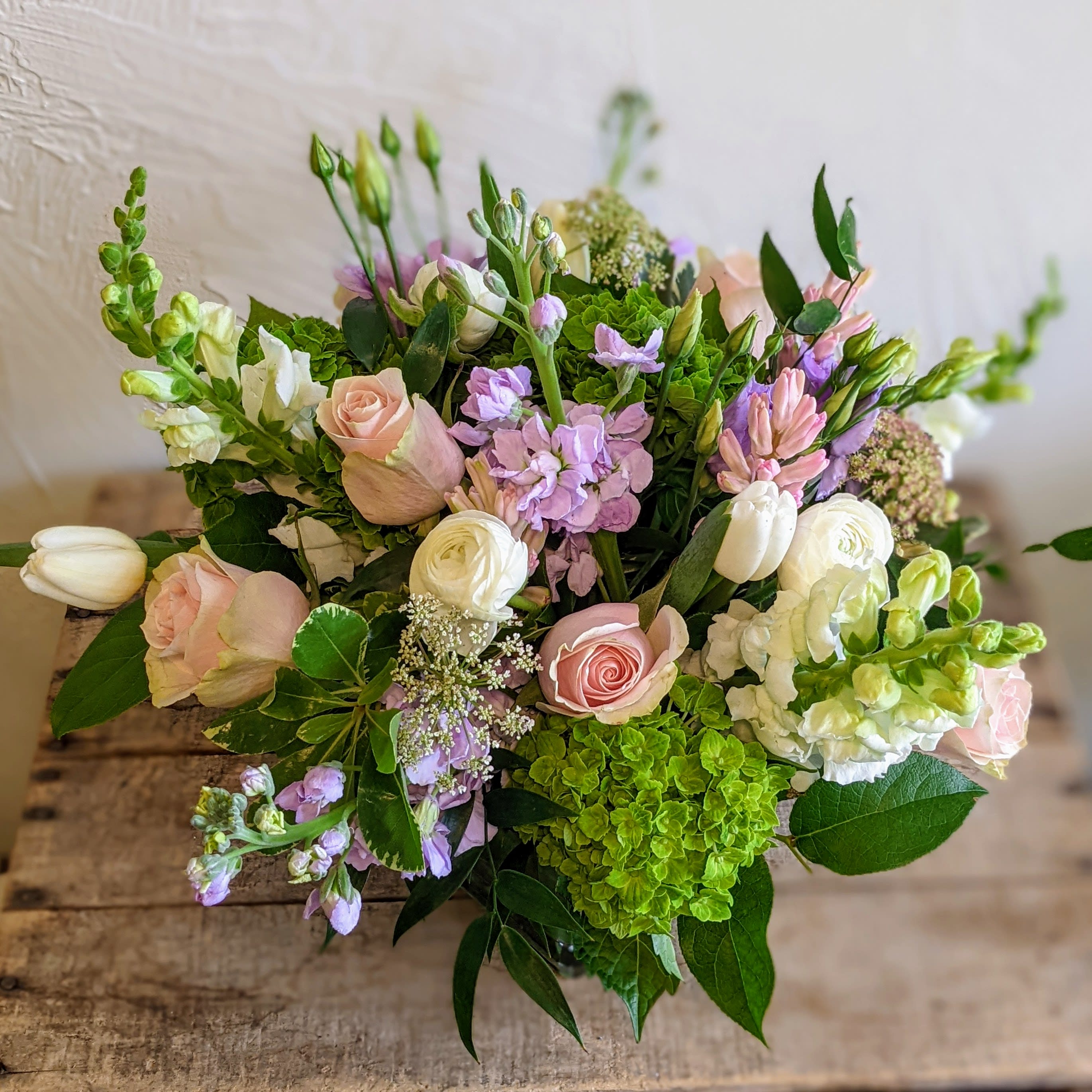 Pastel arrangement of roses, tulips, hydrangea and mixed blooms in a low glass vase