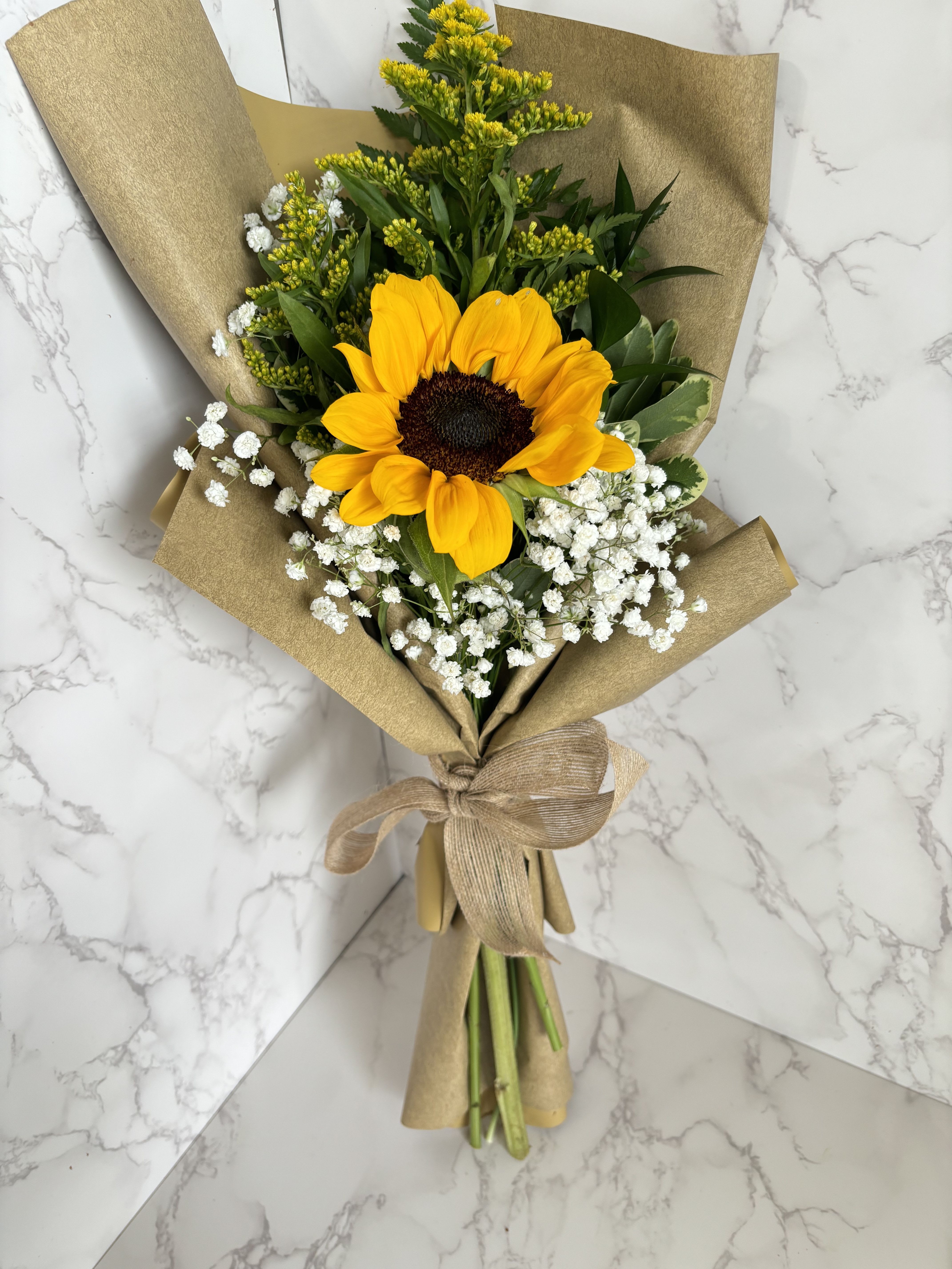 Sunflower bouquet wrapped in brown paper with a ribbon