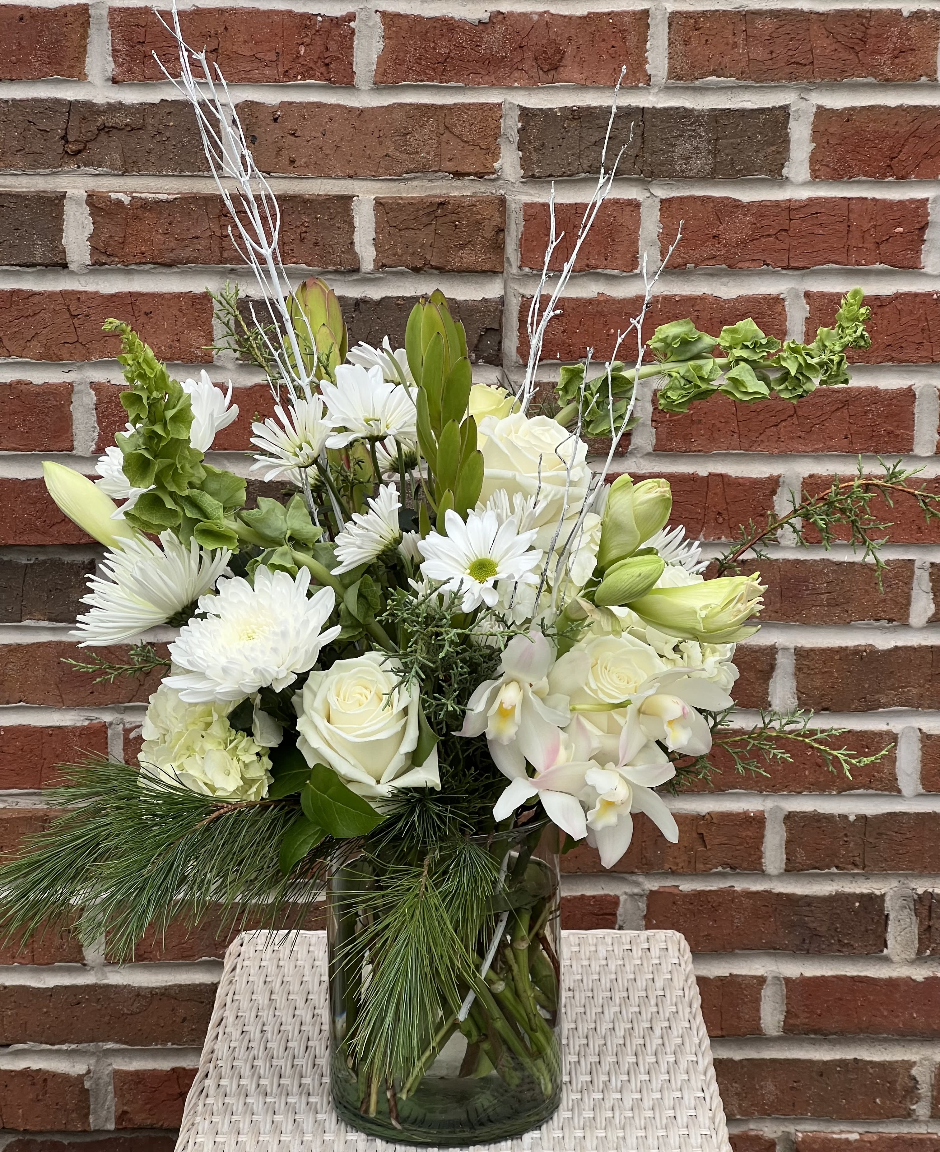White flowers arranged in a glass vase with greenery and branches