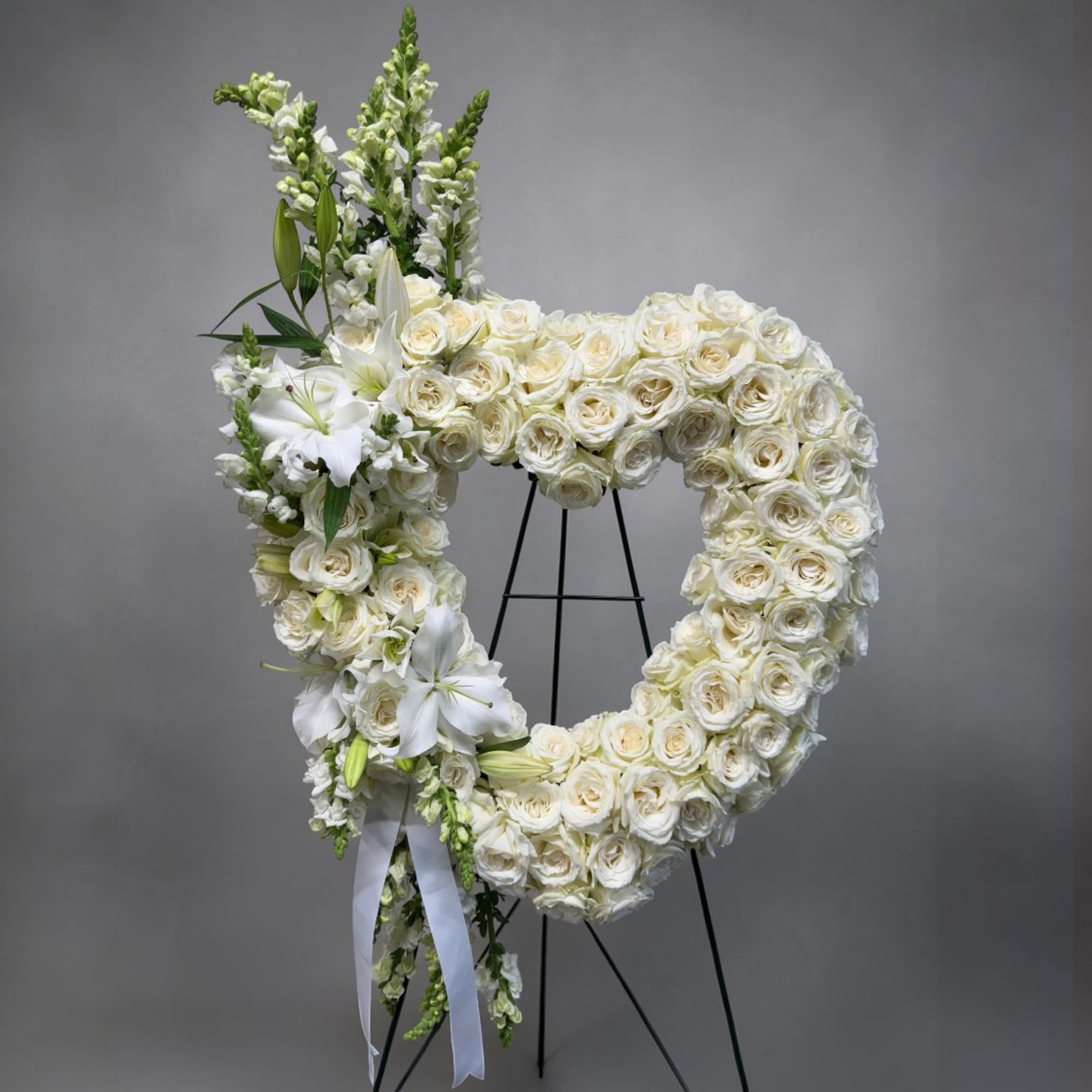 Eternal Love Heart Wreath - A pristine, elegantly designed wreath made of white roses accented with lilies and snapdragons. The wreath can be designed using any color of roses or a combination of colors. 