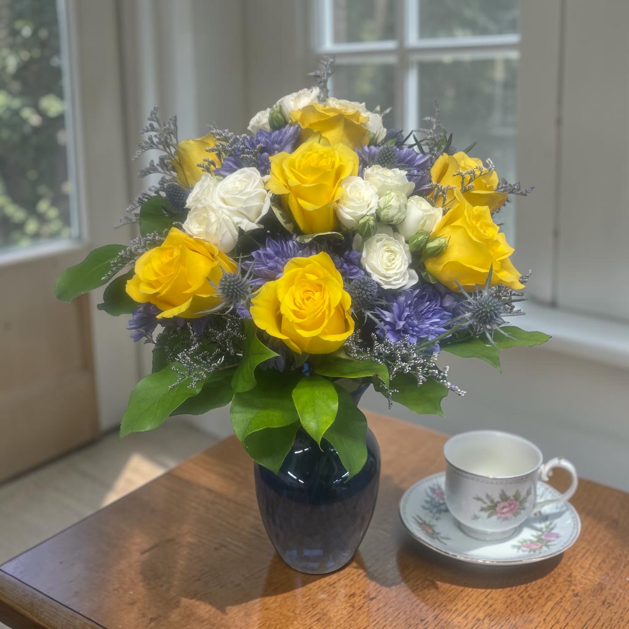 The Sun and The Moon  - Brighten the day with this arrangement which includes yellow roses, naturally blue chrysanthemums, and white spray roses arranged in a blue vase.