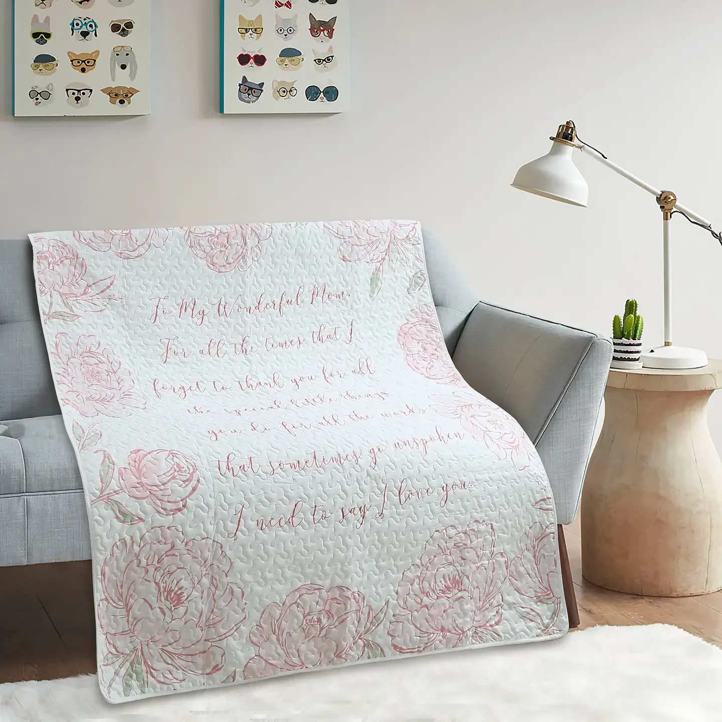 Wonderful Mom Quilted Throw - A soft white quilted throw printed with pale pink floral illustrations and a long cursive message addressed to a mother makes a tender gift that reads like a warm hug. This flower arrangement companion for Mother's Day or everyday appreciation pairs the comfort of a 50" x 60" blanket with a sentimental design that helps the person you're thinking of feel seen and cherished-perfect for celebrating a mom on her special day or adding a gentle touch to routine moments.  The throw's quilted texture and muted pink blooms sit beautifully against neutral décor; the product is pictured draped over a light gray sofa in a contemporary living room with a white floor lamp, small round side table, potted cactus, and framed prints, suggesting how effortlessly it layers into casual, cozy spaces. Measuring 50 x 60 inches, the blanket is large enough for curling up on the couch yet light enough to fold over a chair as décor; it will arrive wrapped for home delivery so it's ready to gift without extra fuss.  Whether you're marking Mother's Day, a birthday, or simply saying "I'm thinking of you," this cuddly throw delivers warmth, sweetness, and a lasting reminder of affection that fits everyday life. Care instructions: machine wash gentle; tumble dry low to keep the quilting plush.