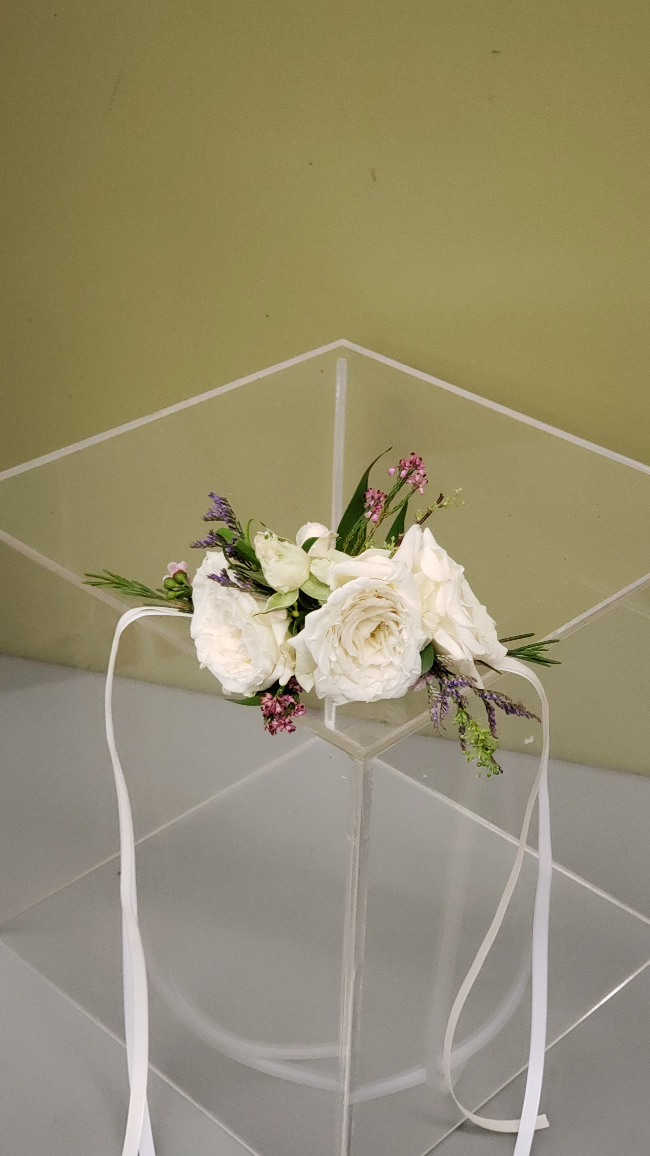 White floral crown with small pink and purple flowers on a clear stand