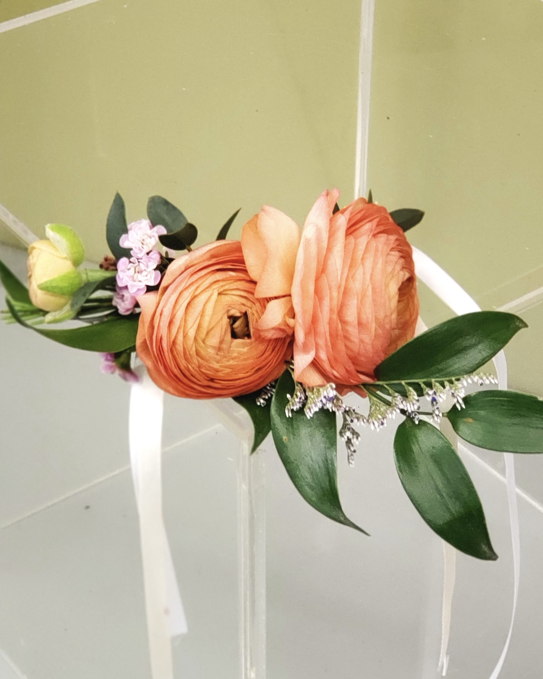 Orange and peach floral wrist corsage with white ribbon