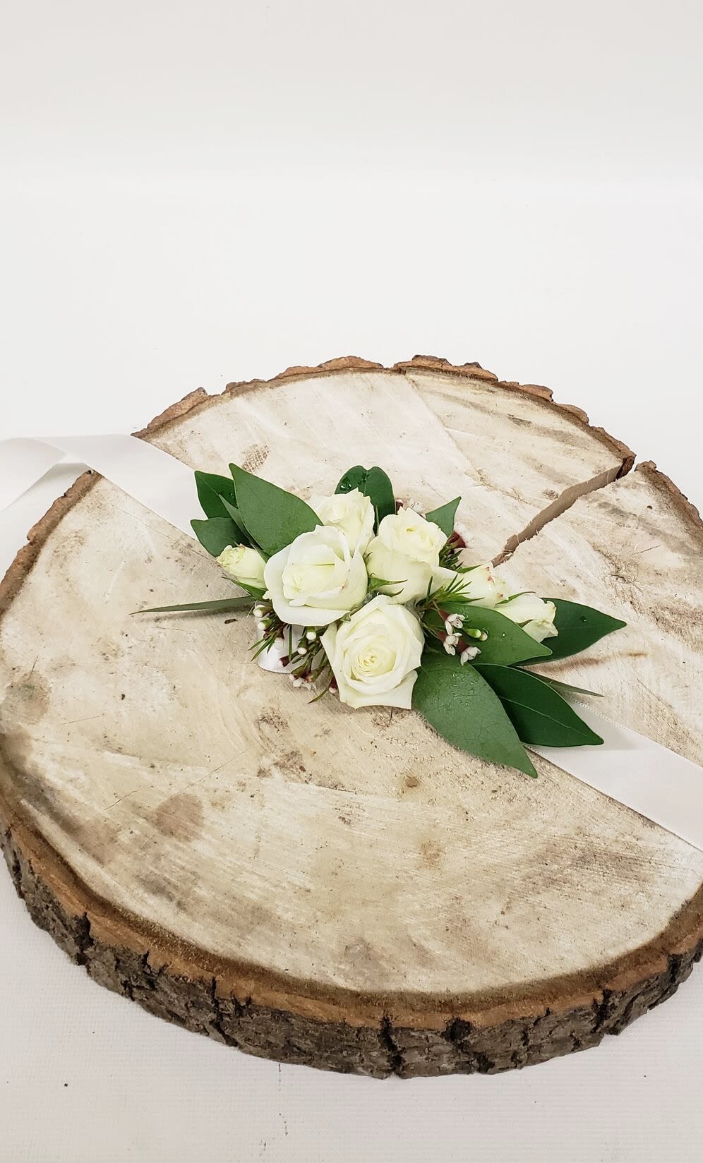 White rose boutonniere on a wood slice with white ribbon