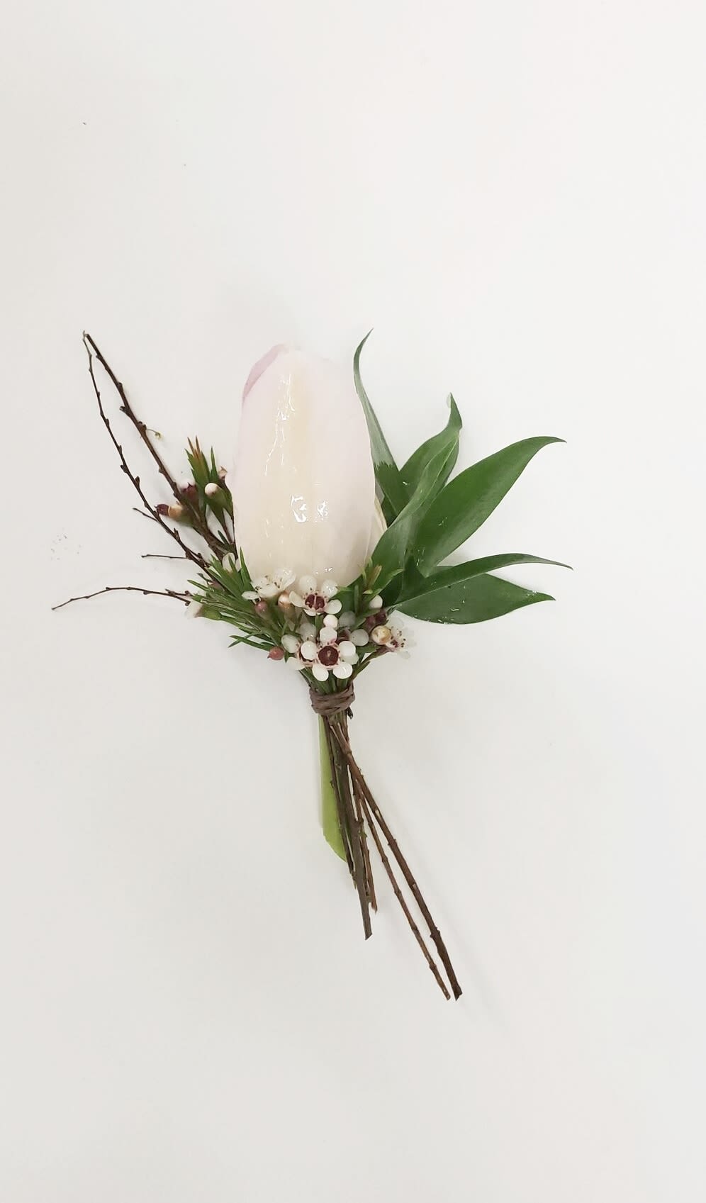 White candle boutonniere with green leaves and small berries
