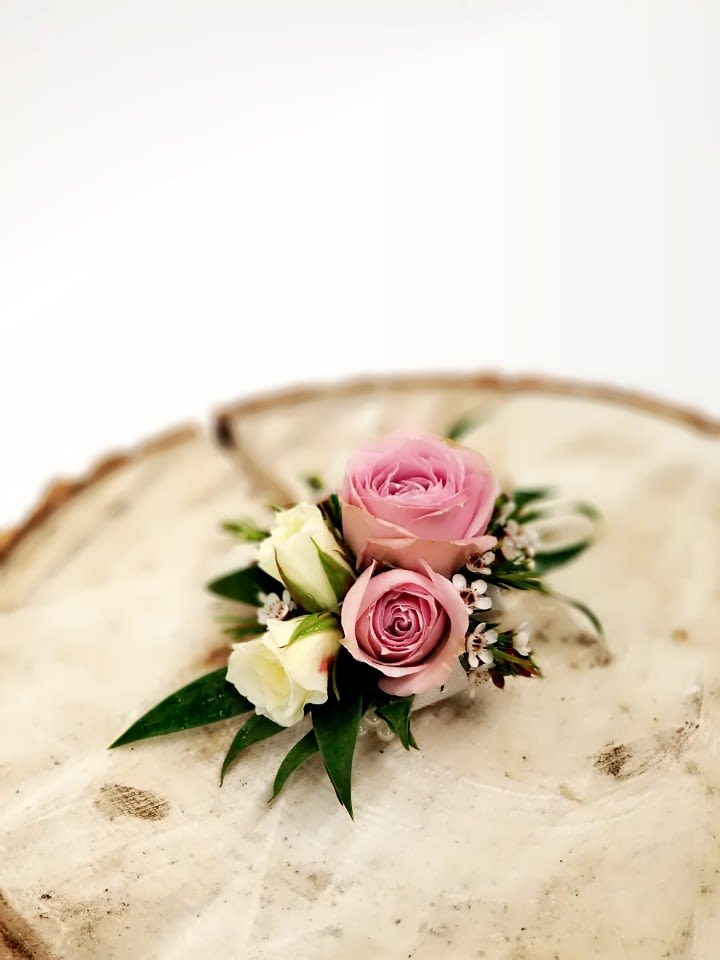 Small pink and white rose boutonniere on a cream hat