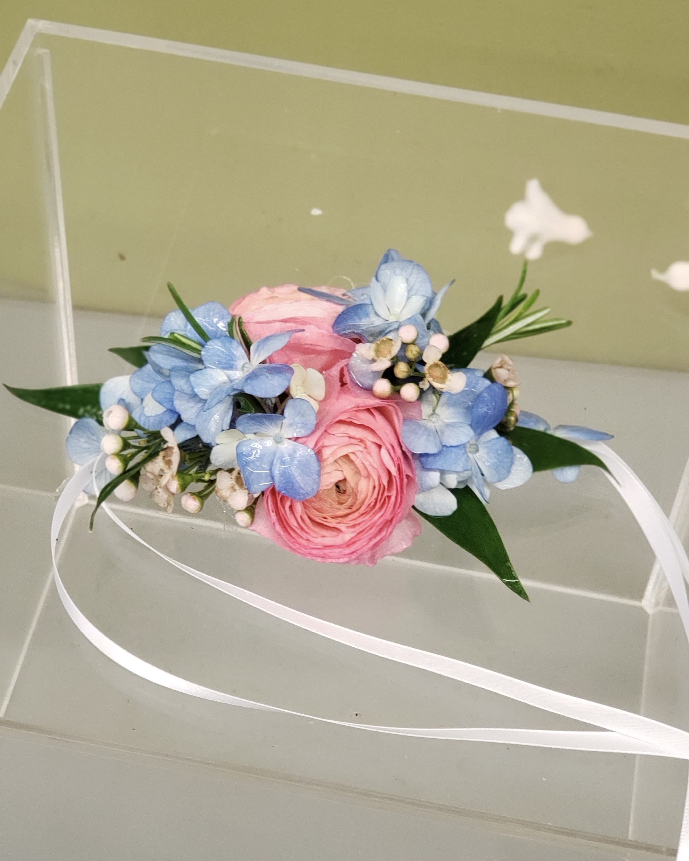 Pink and blue floral wrist corsage with white ribbon