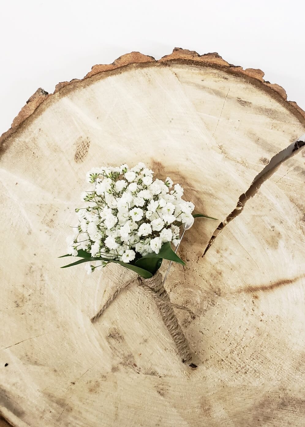 Small white baby's breath bouquet tied with twine on a wood slice