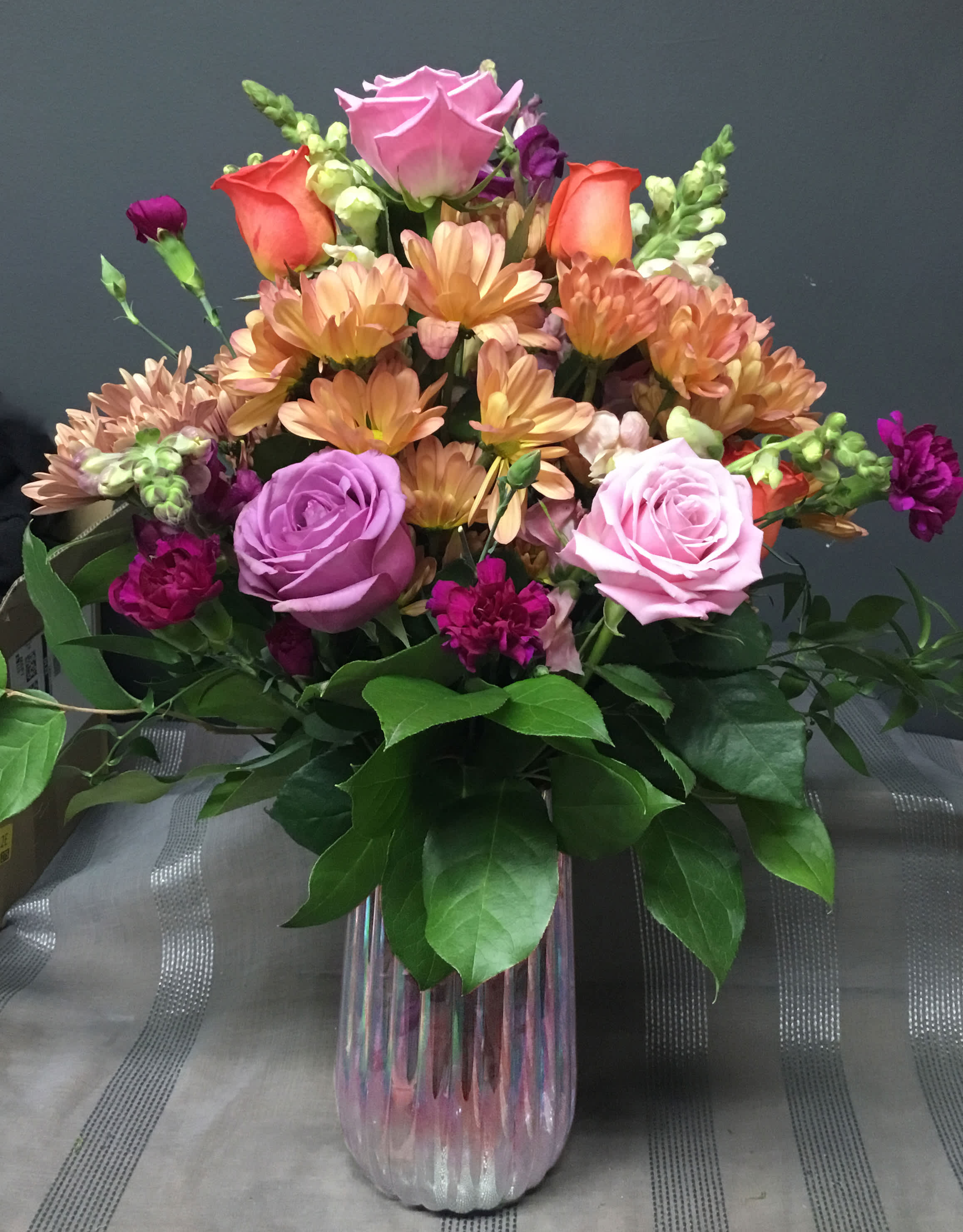 Mixed bouquet of roses, chrysanthemums, and snapdragons in a glass vase