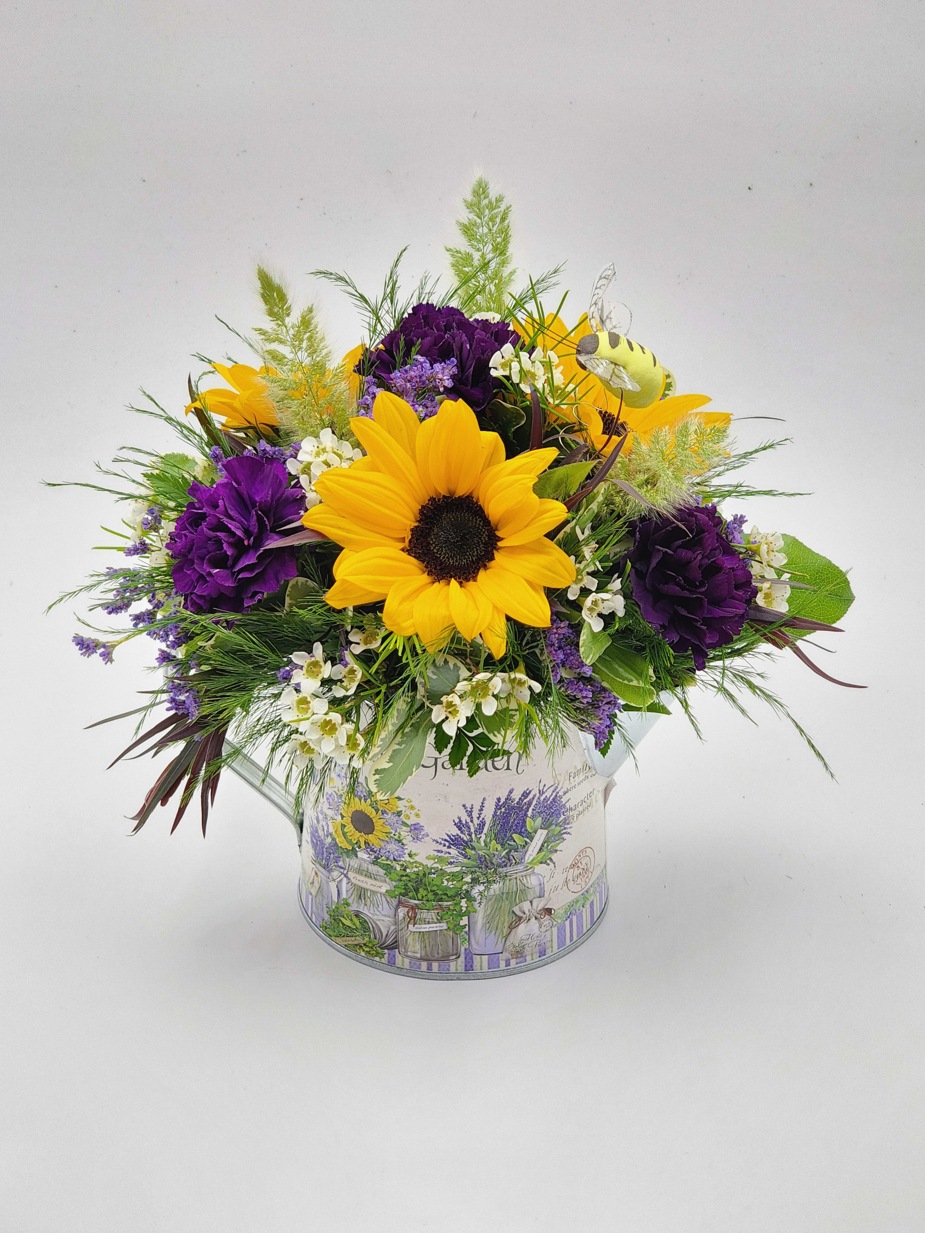 Beejeweled - A lovely small arrangement featuring small sunflowers, dark purple carnations and fillers in an adorable tin pitcher with a bee accent.  Roughly 11.5x9.5"