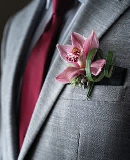 Pink orchid boutonniere pinned to a gray suit jacket