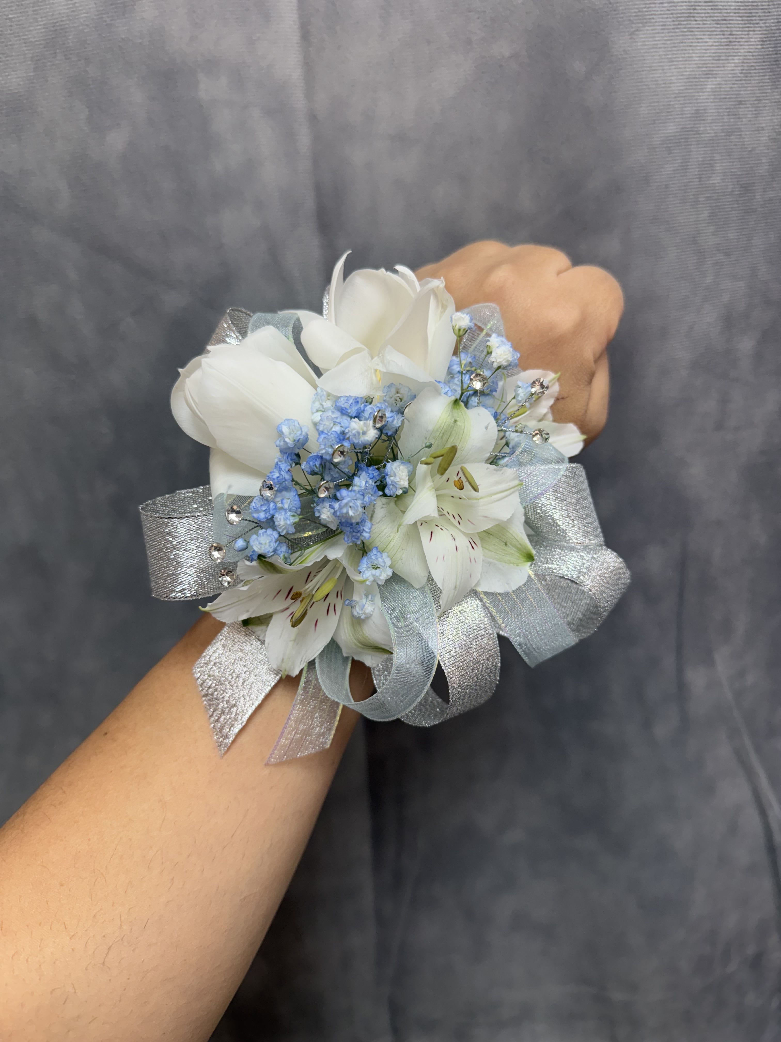 White tulips alstroemeria silver blue corsage - White alstroemeria wrist corsage with white tulips , blue filler accents and shiny silver ribbon on a pearl wrist band-delicate perfect for proms . The corsage can be customized upon request 