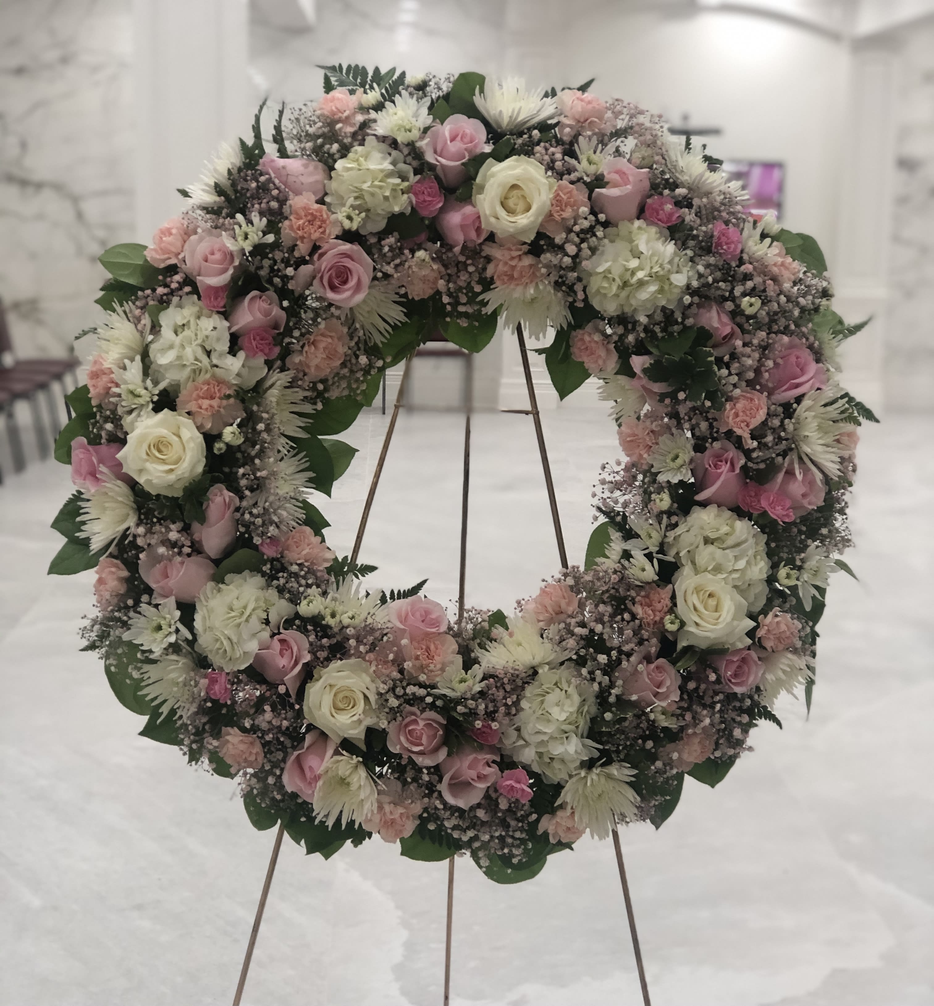 Large floral wreath of pink and white roses on a stand
