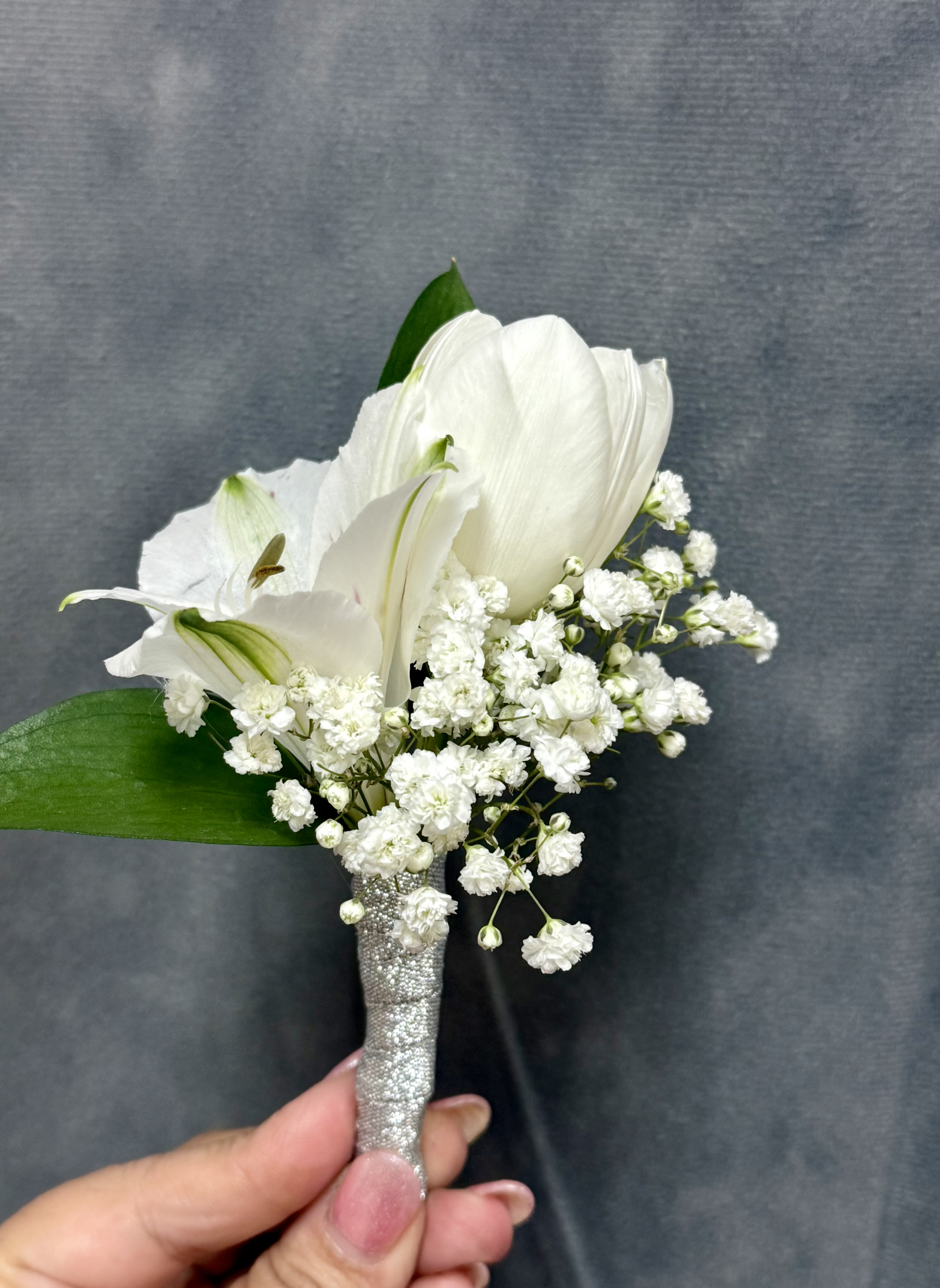 White tulips alstroemerias boutonnière  - White tulips and alstroemerias with  baby's breath and green leaves, compactly arranged with a sparkly silver stem wrapped 