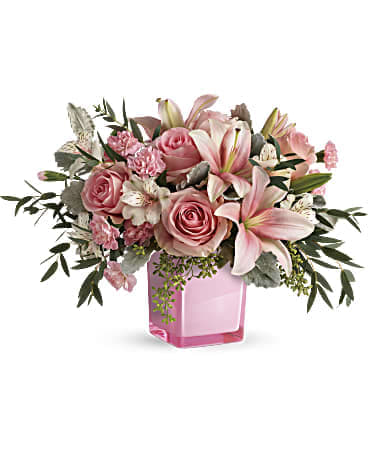 Pink roses and lilies arranged in a pink glass vase