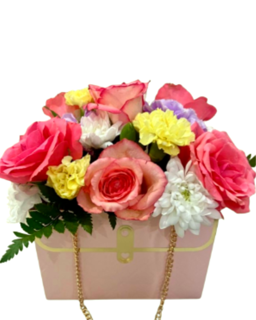 The Radiant Mother Purse Arrangement - A vibrant and joyful masterpiece. This stylish pink purse box is blooming with premium coral-tipped roses, sunny yellow carnations, and crisp white chrysanthemums. A chic and artistic gift that perfectly captures the warmth of Mom’s love.