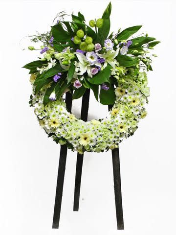 Standing floral wreath with white and green flowers on a black easel