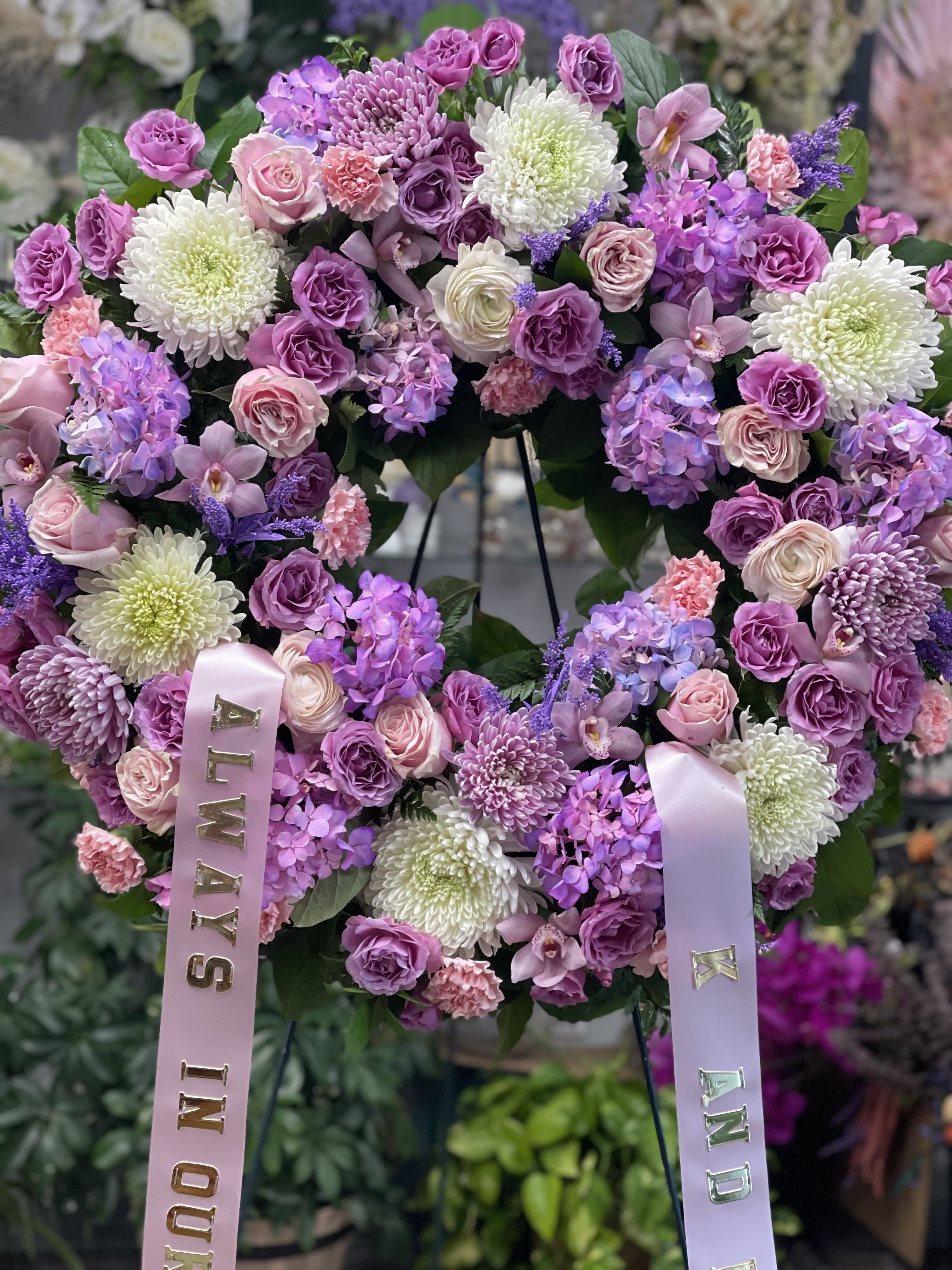 Heart-shaped floral wreath with pink and purple blooms and satin ribbons
