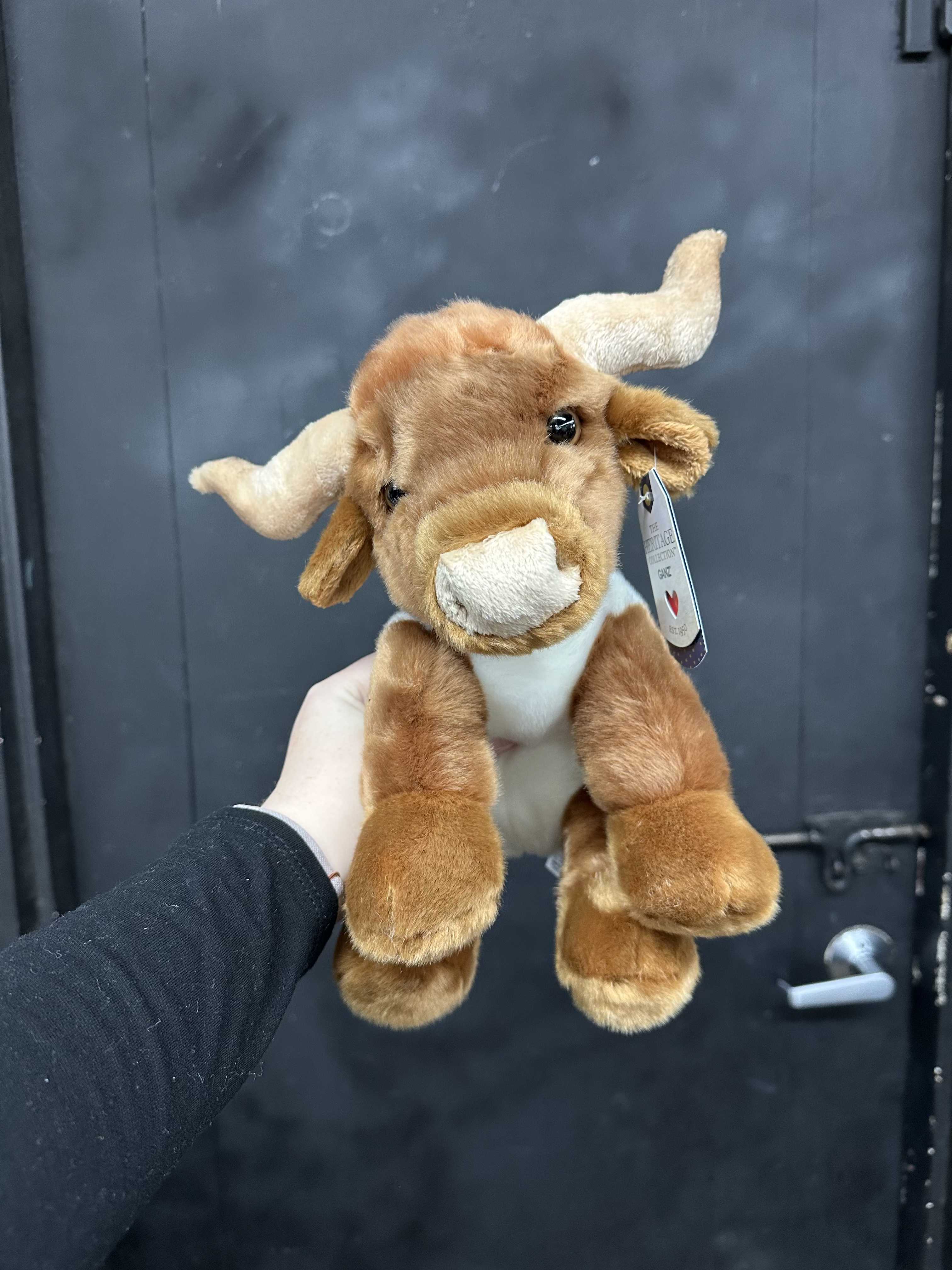 Brown plush cow toy with white horns and snout being held up