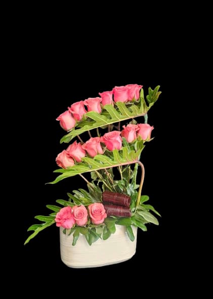 Pink roses arranged in a white basket with layered greenery