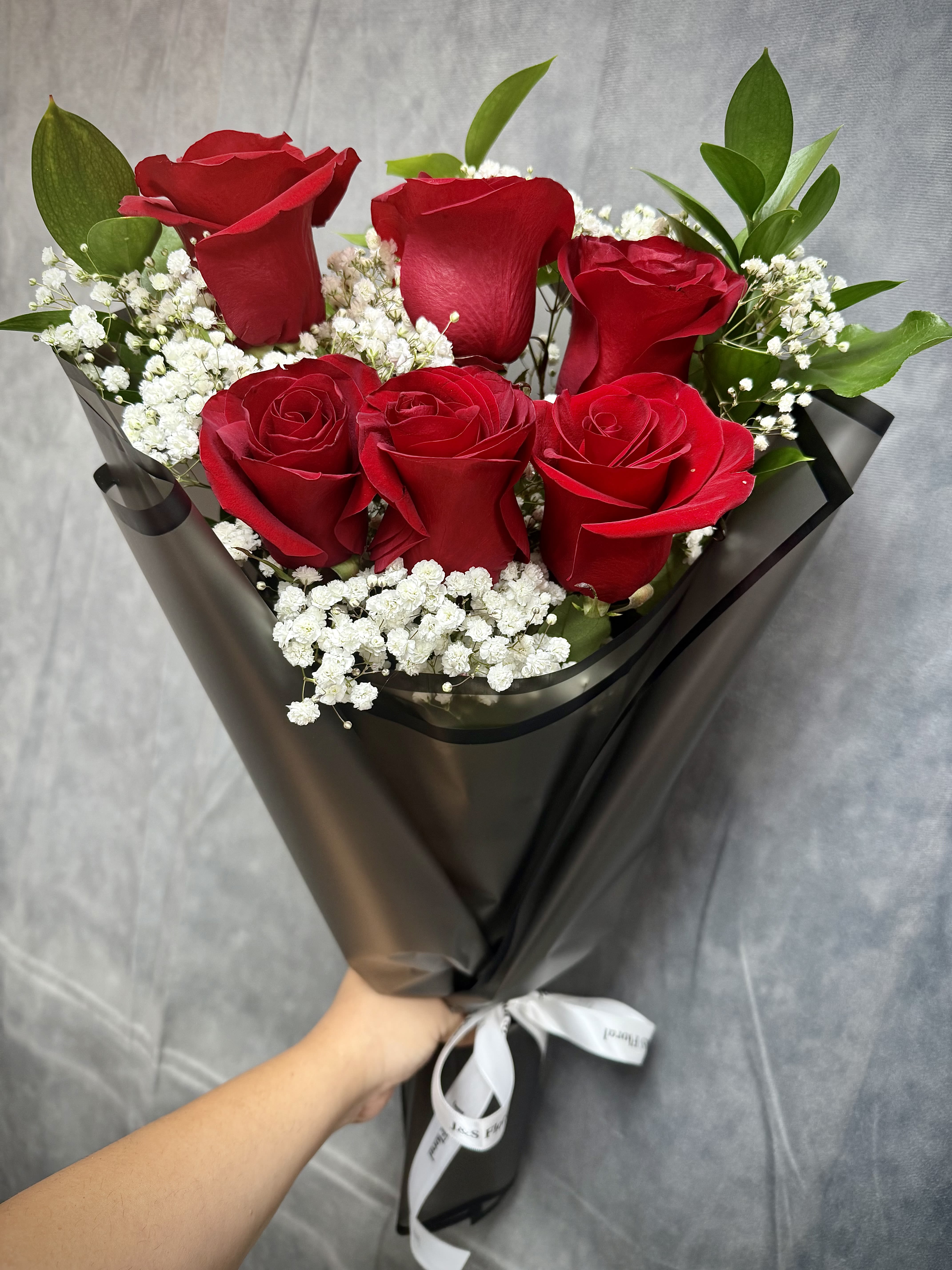 Bouquet of red roses with white baby's breath in black wrap