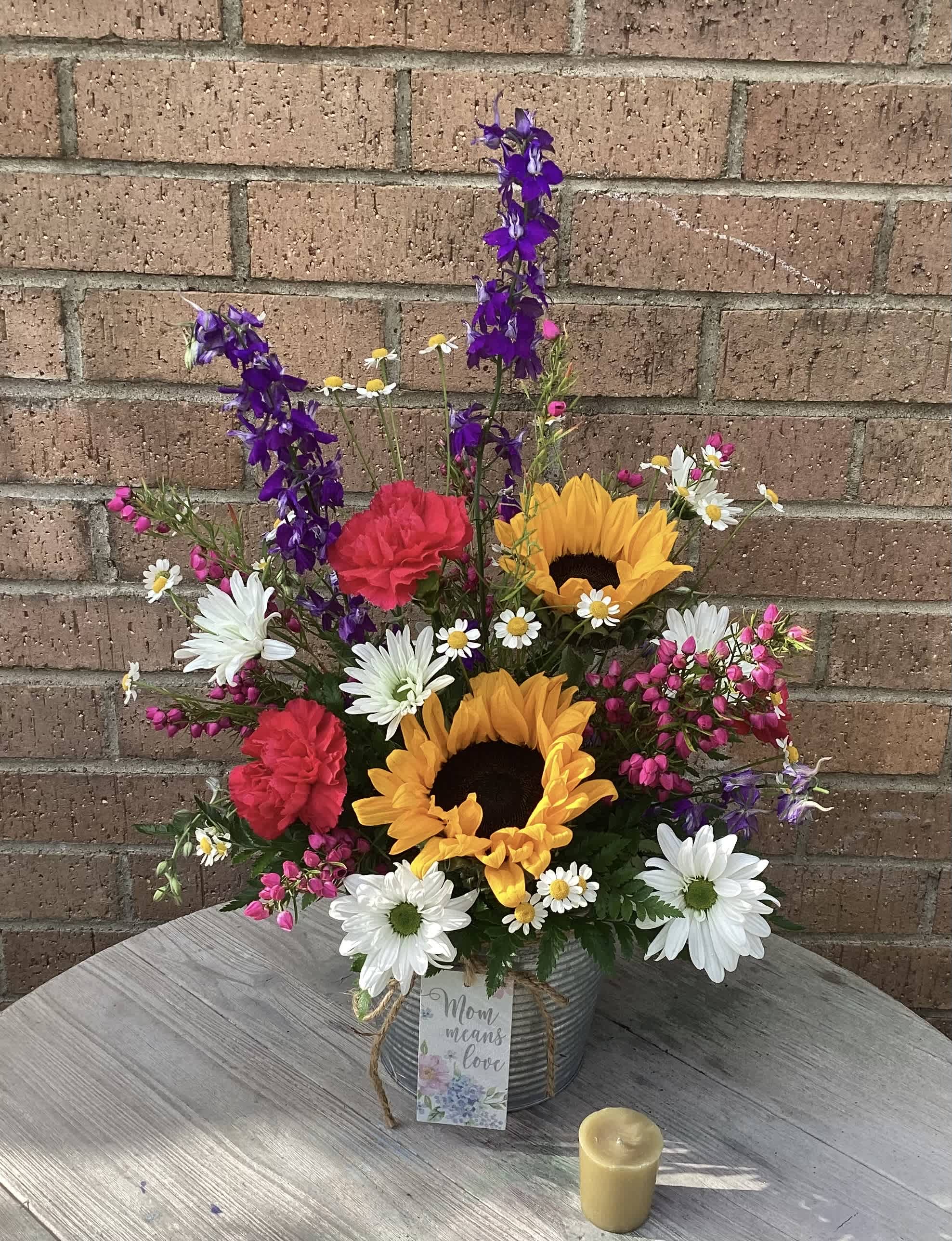 Mixed bouquet with sunflowers, daisies, carnations, and purple spikes in a tin container
