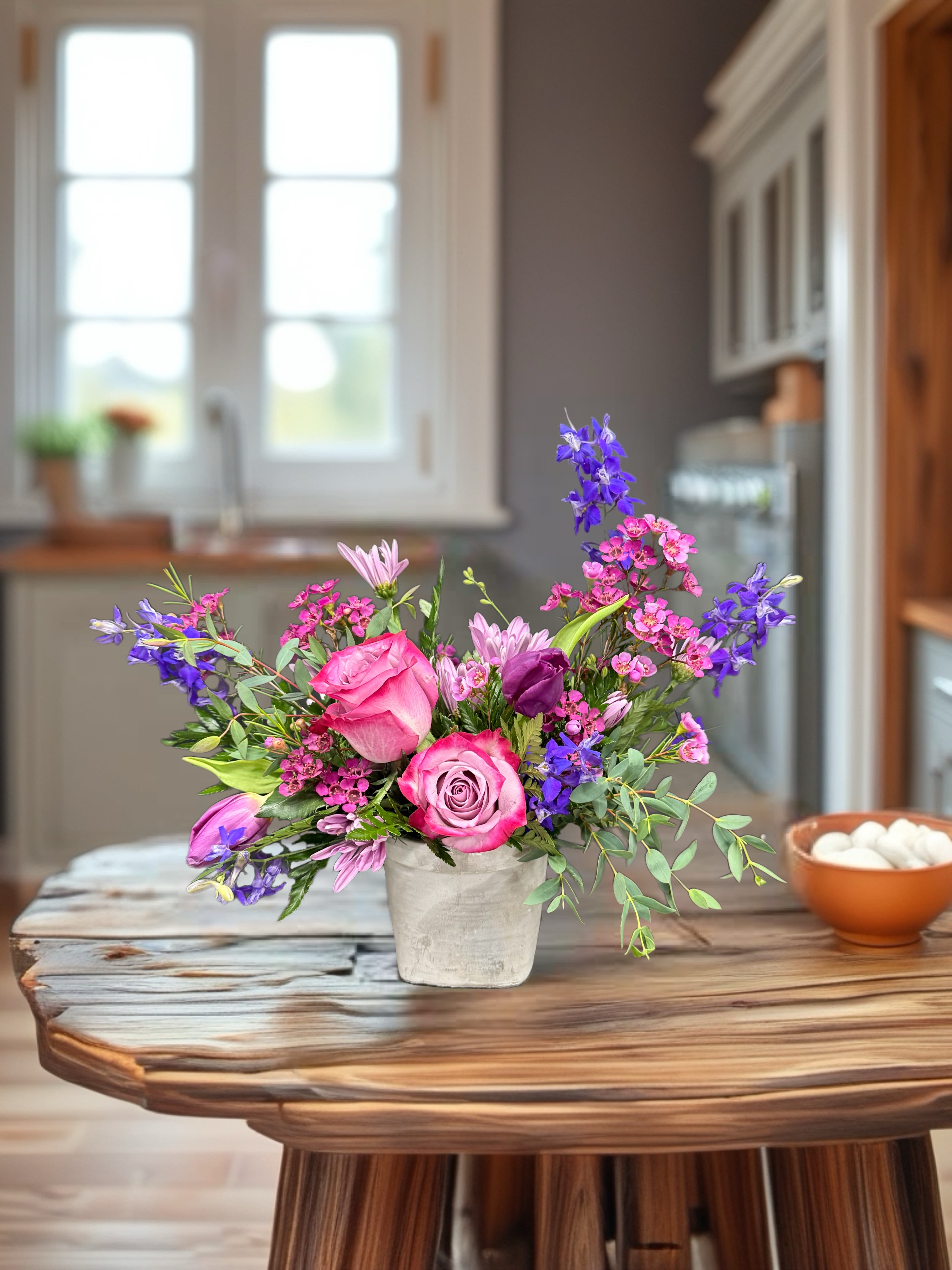 Pink and purple mixed bouquet in a white vase on a wooden table
