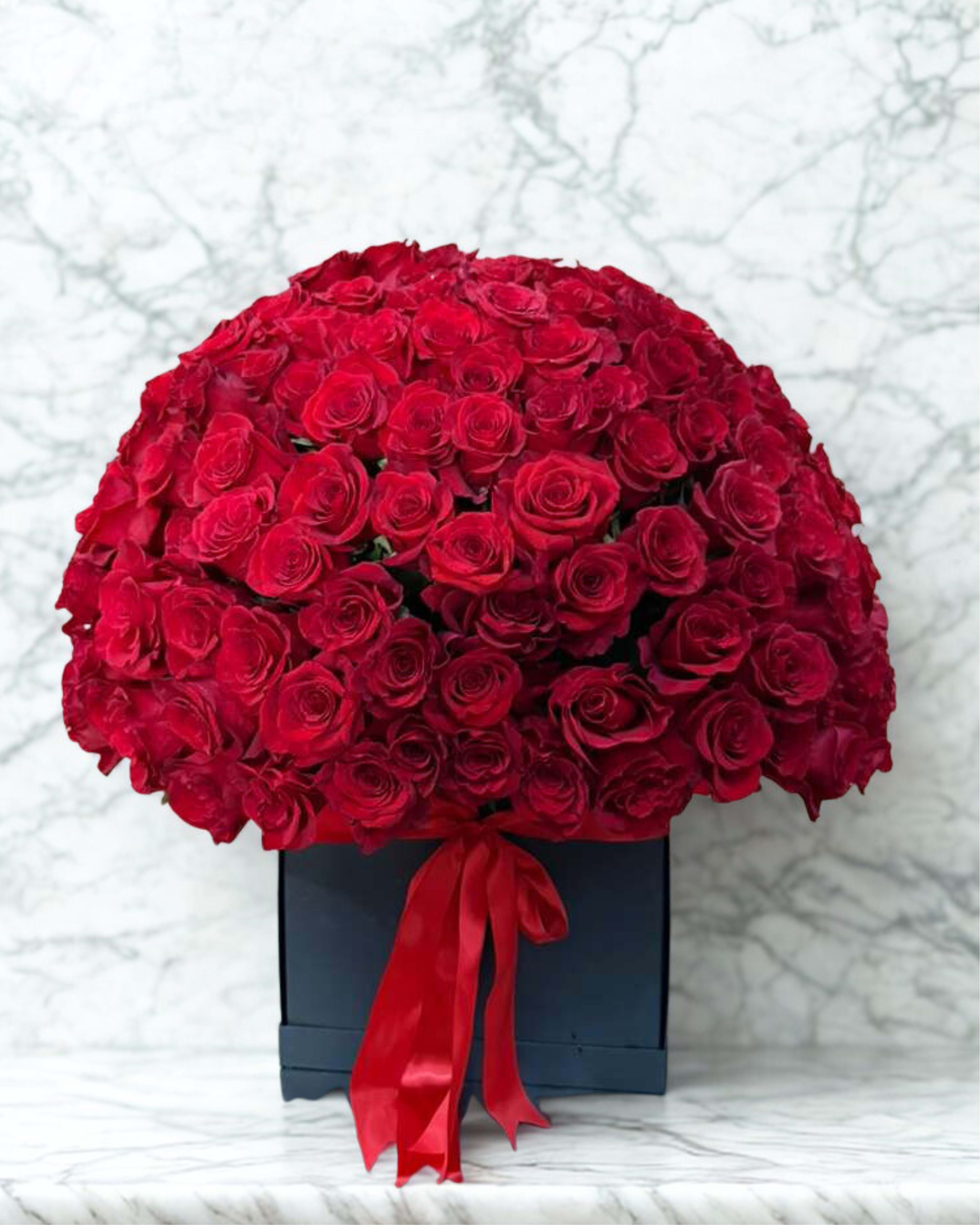 Large bouquet of red roses in a black box with a red ribbon