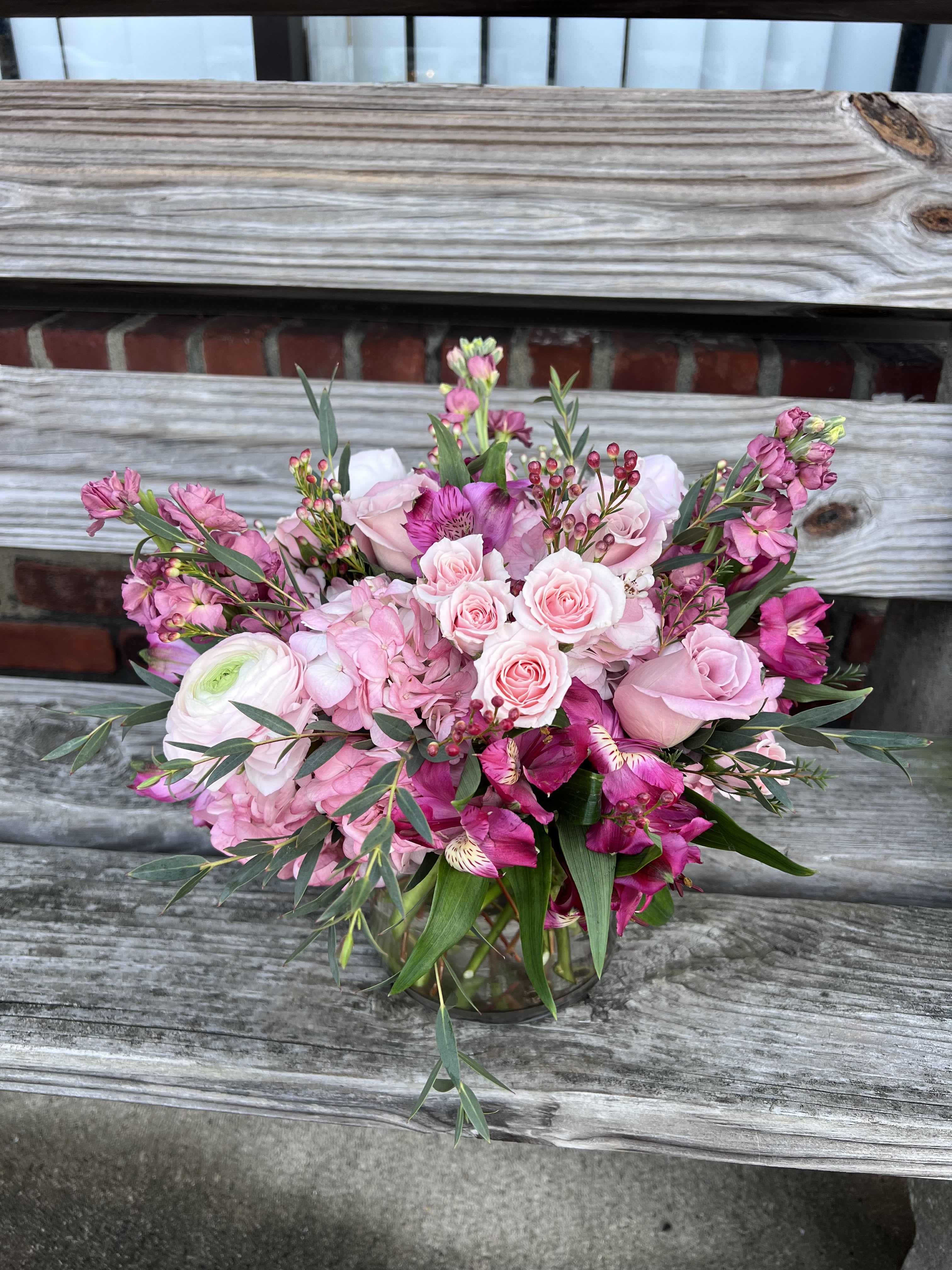 Pink and magenta mixed flower arrangement with roses and hydrangeas in a clear glass vase