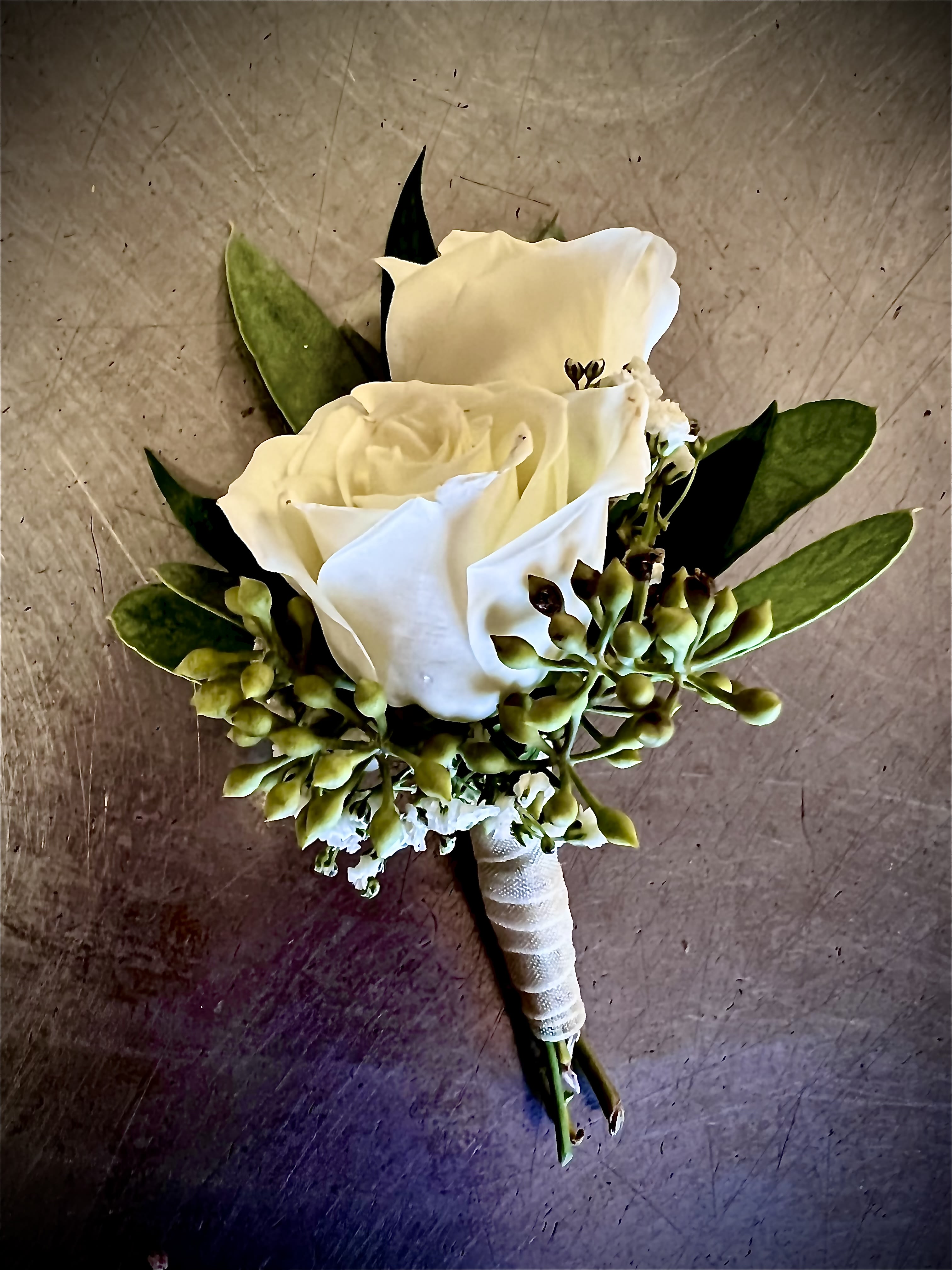White rose boutonniere with green buds and leaves