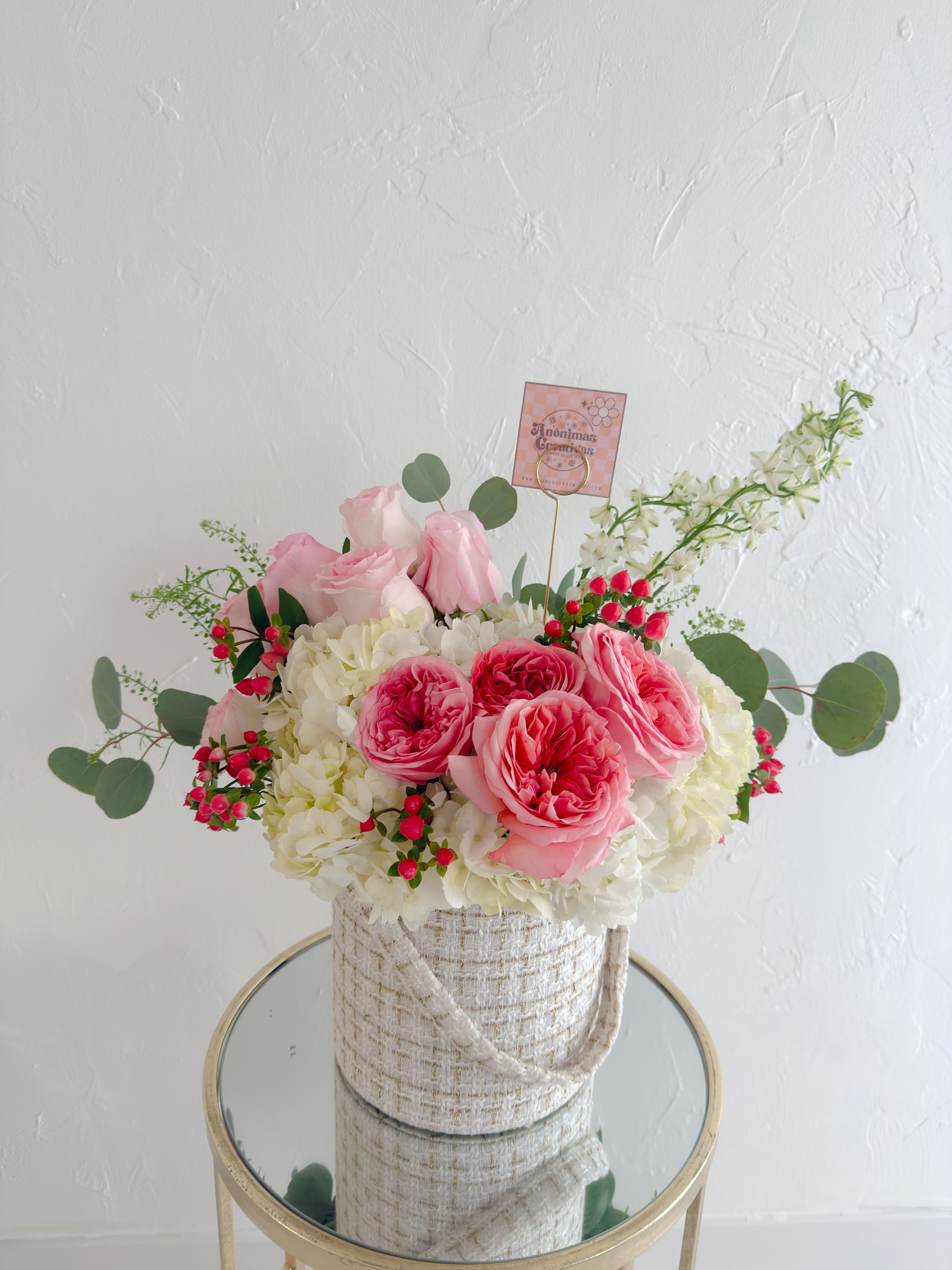 Lorena  - Elegant and delicate floral arrangement featuring pink roses, white hydrangeas, and accents of hypericum and eucalyptus. Designed in a neutral textured base, it blends romance and freshness—perfect for gifting or stylish décor. 