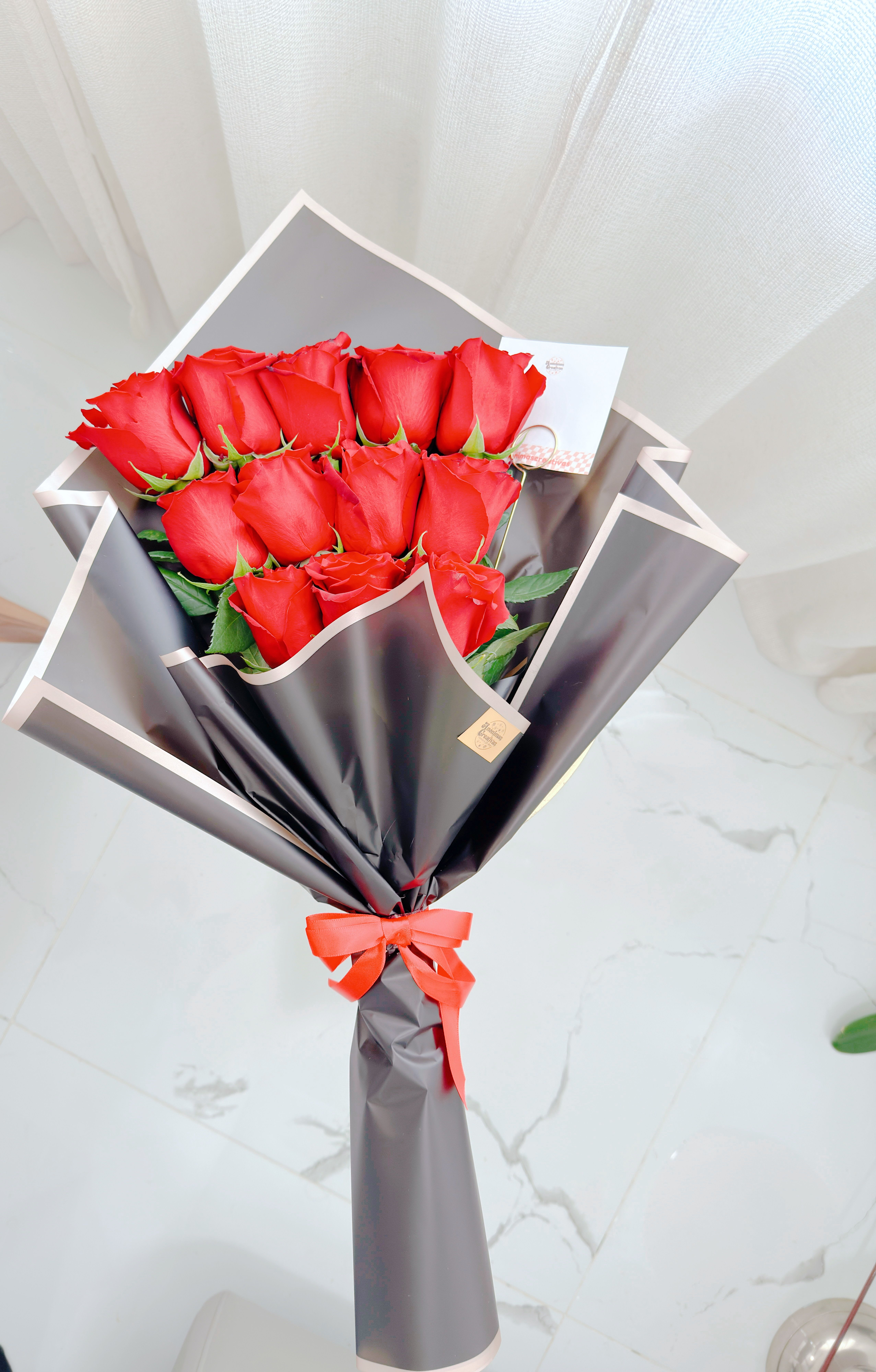 Docena de Rosas - Elegant bouquet of vibrant red roses, beautifully wrapped in premium black paper and finished with a matching ribbon. A timeless and romantic choice, perfect for expressing love, passion, and special moments.