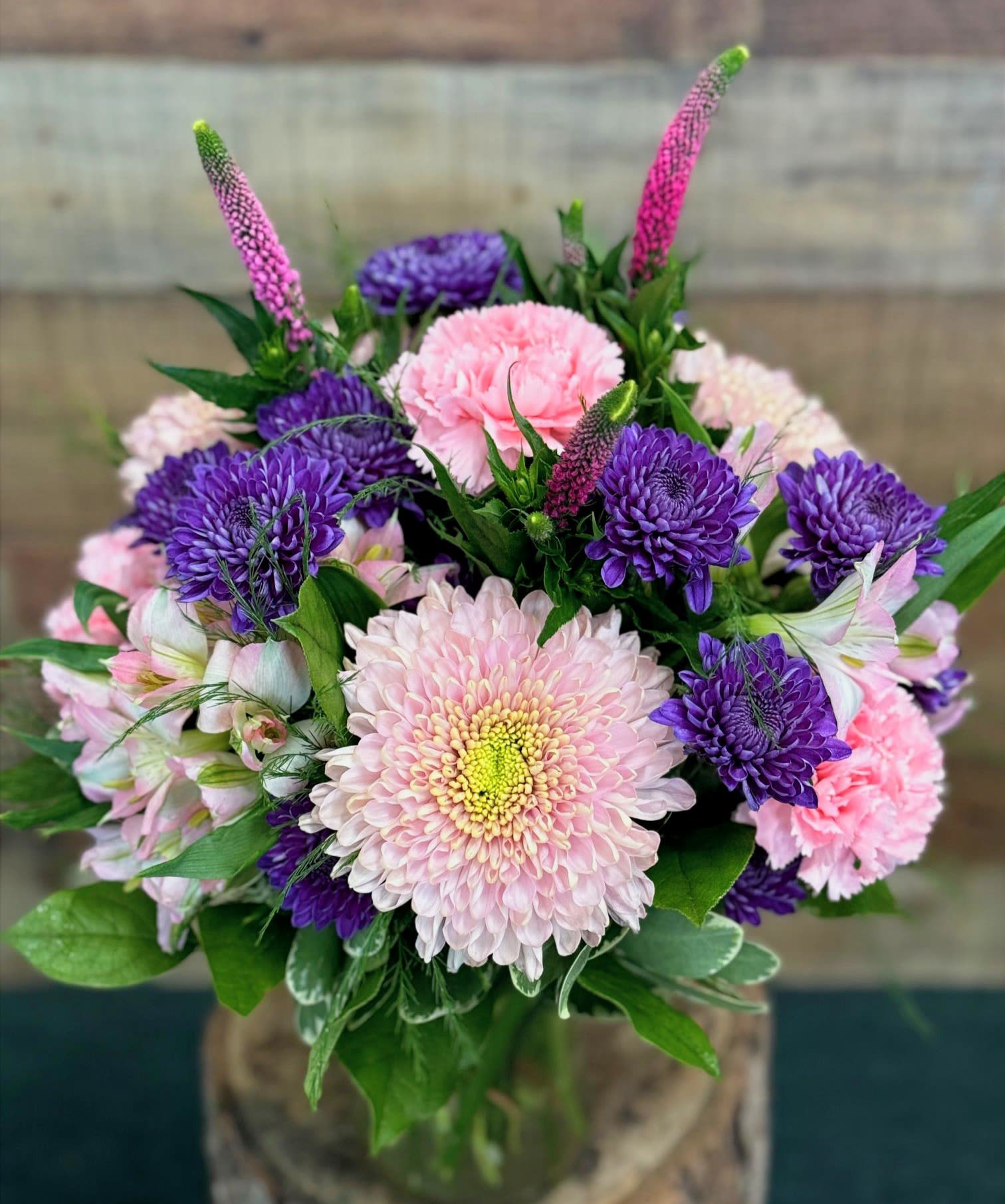 Romance in Bloom - Deep purples and romantic pinks designed in a clear glass vase using many long lasting varieties.