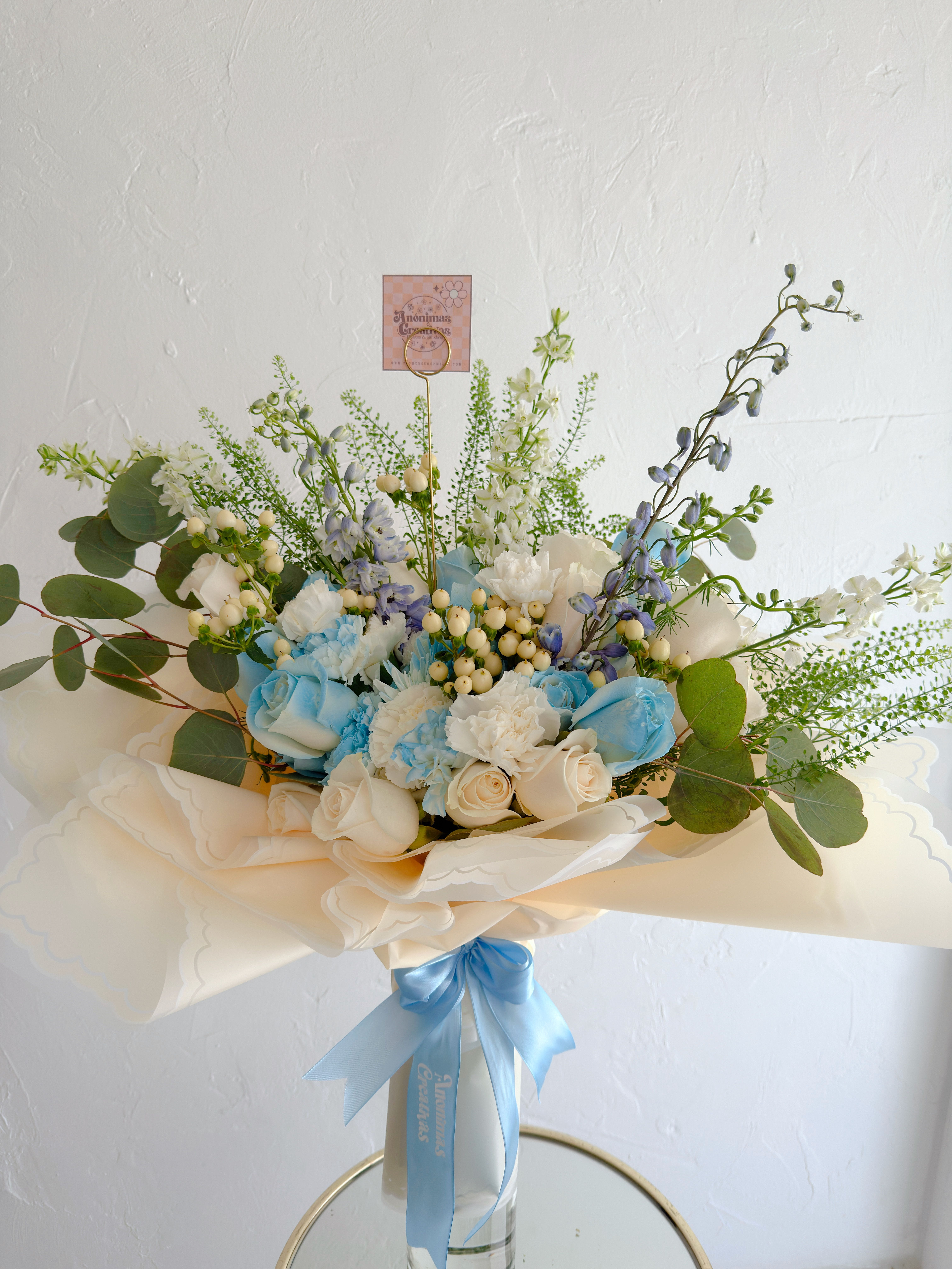 Bouquet boy  - Elegant bouquet in soft blue and white tones, featuring roses, carnations, and delicate seasonal blooms, accented with hypericum berries and fresh eucalyptus. Wrapped in premium cream paper and finished with a satin blue ribbon, it’s a fresh, serene, and sophisticated design—perfect for special occasions or thoughtful gifts. 