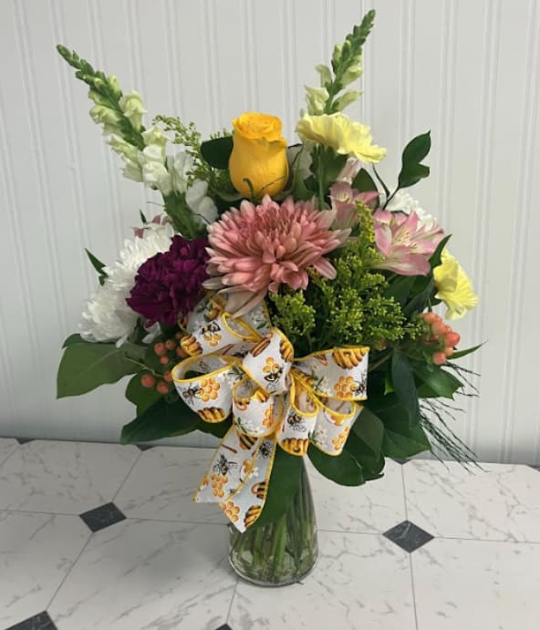Queen Bee - Sweet, bright, and buzzing with charm! Queen Bee is arranged in a trendy “Vibe” vase and features a delightful mix of pink, yellow, purple, and peach blooms. Finished with an adorable bumblebee ribbon, this arrangement is a cheerful way to celebrate someone who deserves the royal treatment.
