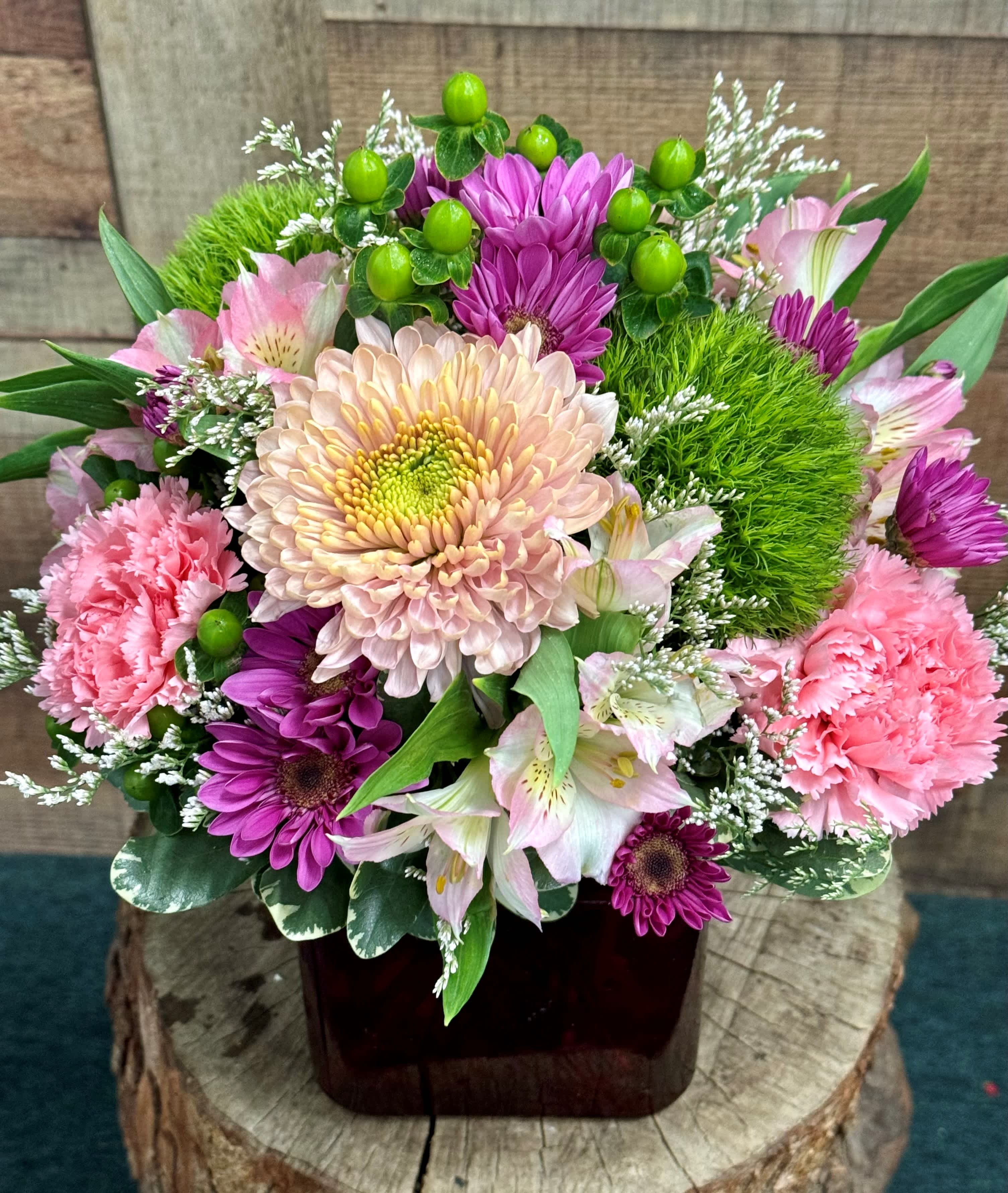 Pink and purple mixed flower arrangement in a dark vase