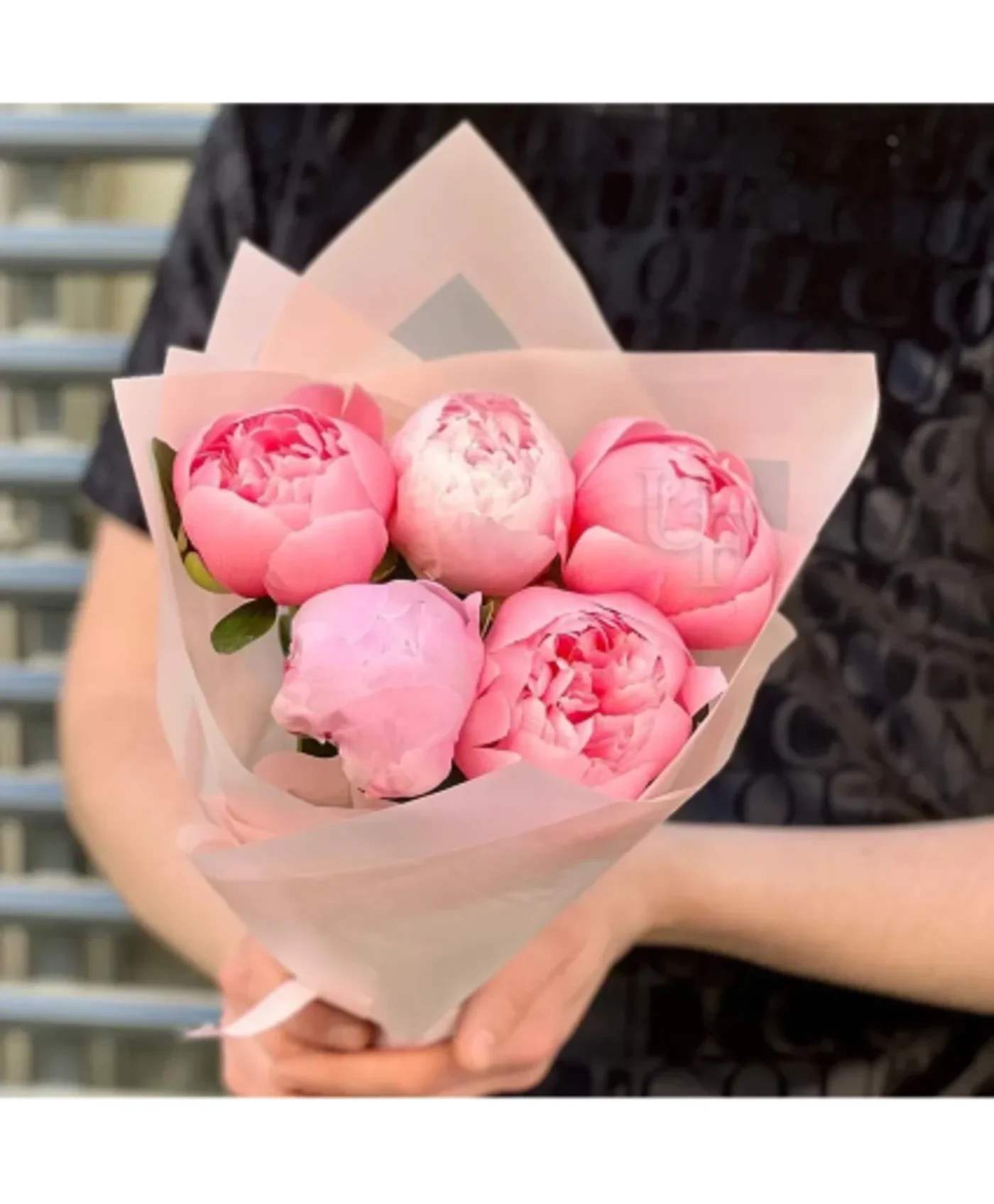 Bouquet of pink peonies wrapped in pale pink paper